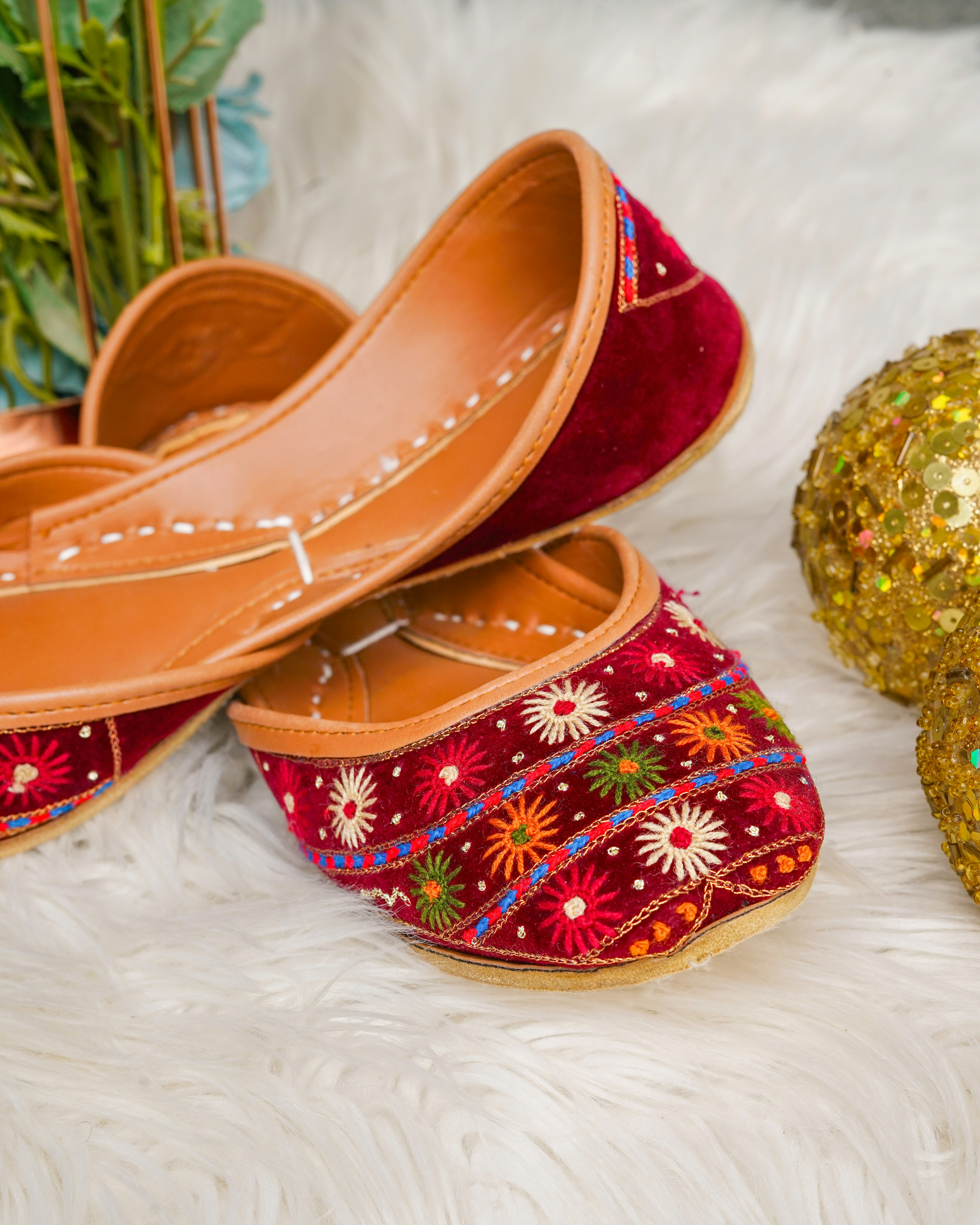 Juttis de veludo vermelho bordados sobre uma superfície branca e fofa