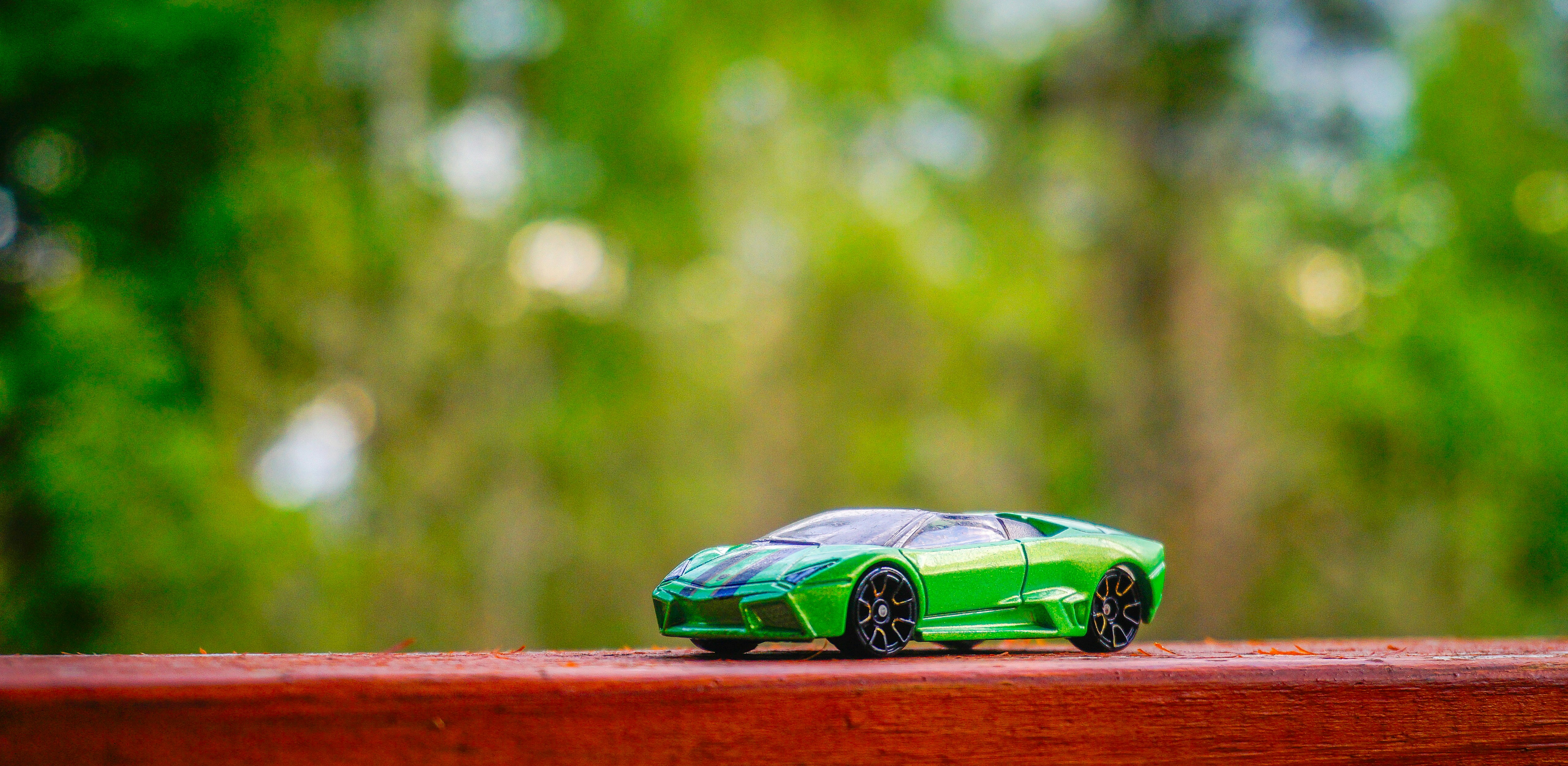 Um carro esportivo verde de brinquedo sobre uma superfície de madeira.