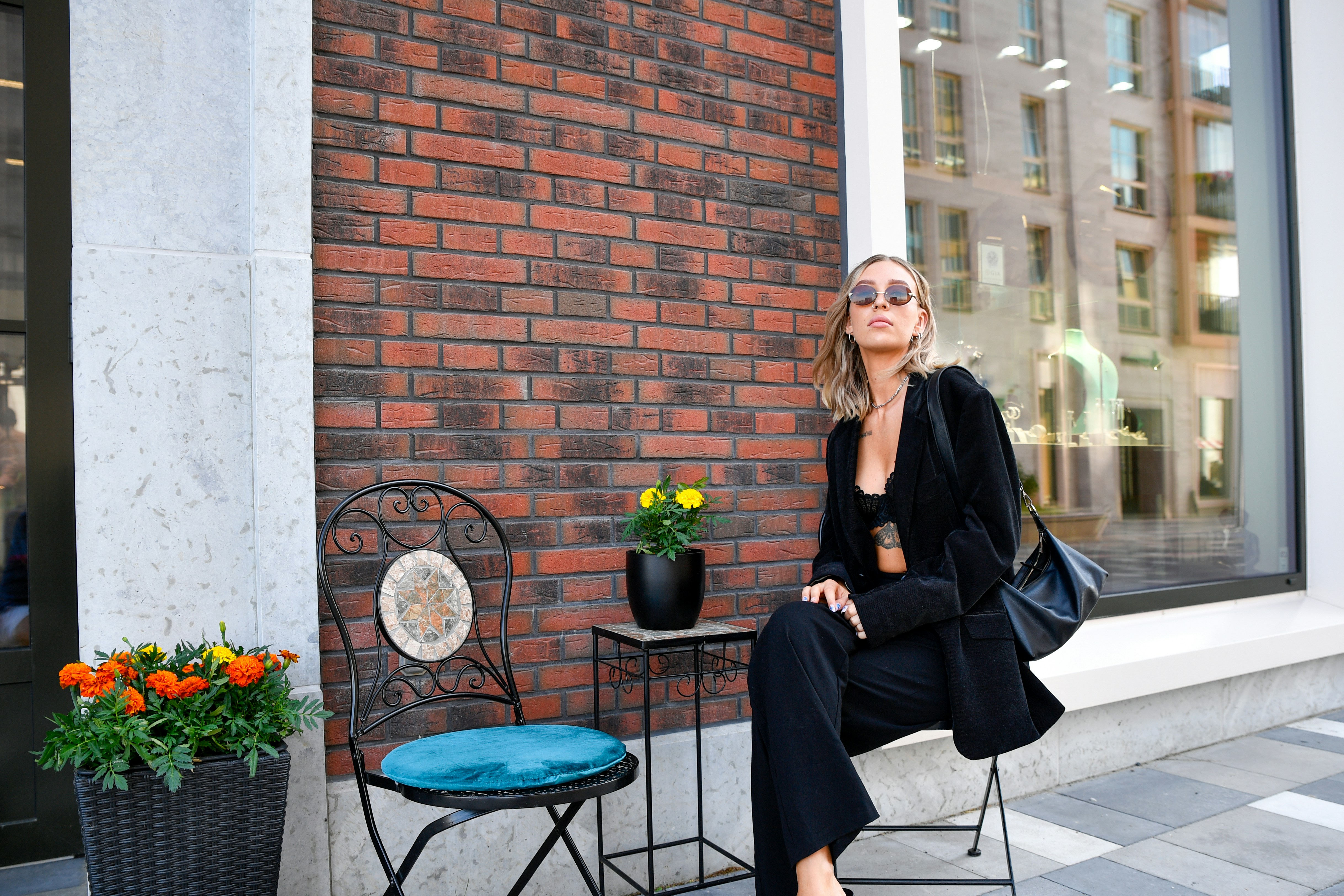 Woman in black suit sitting outside a brick building.