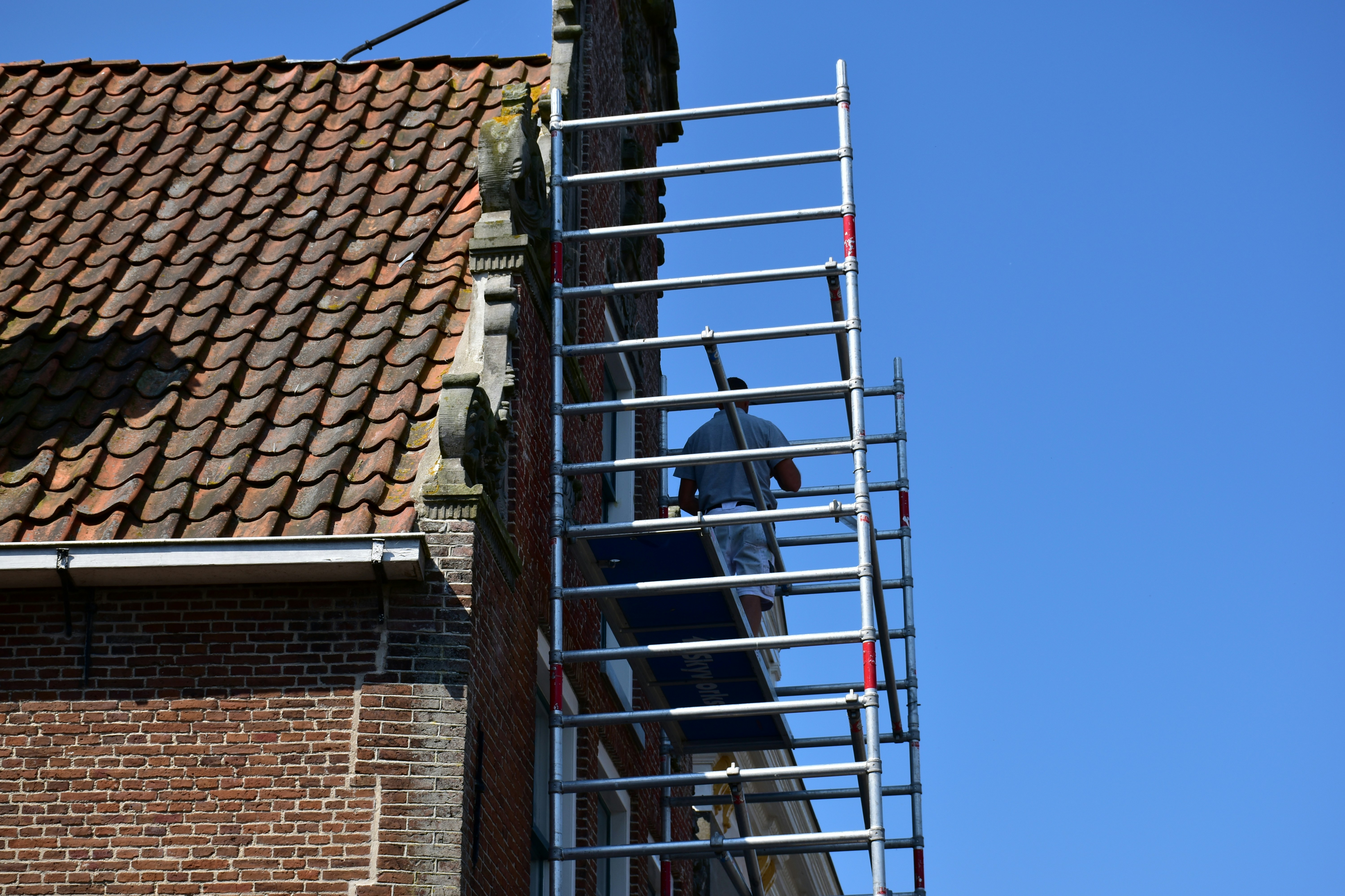 Worker on scaffolding next to brick building