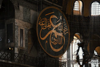 Large arabic calligraphy circle inside a grand building.