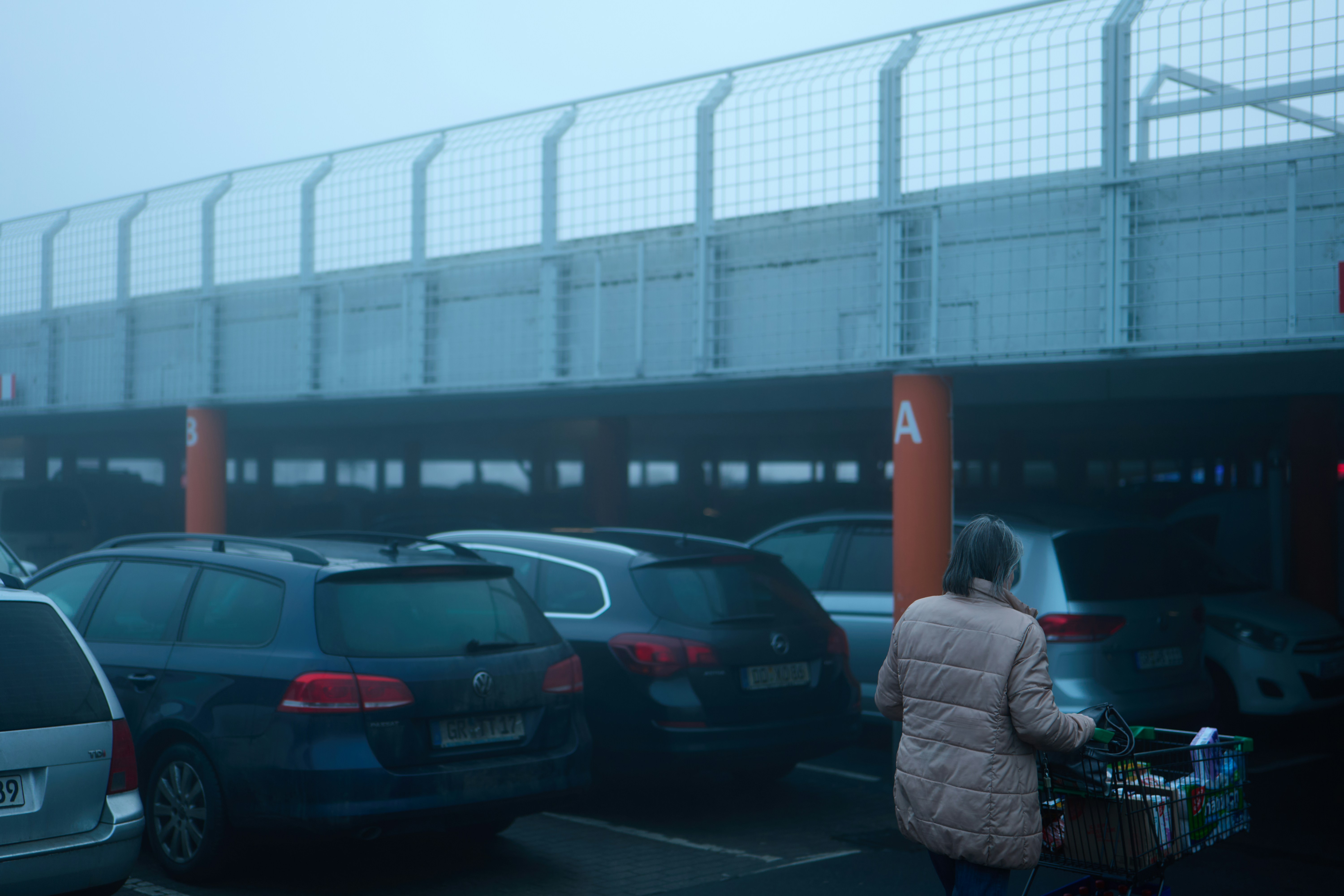 Shopper pushing a trolley through a foggy car park