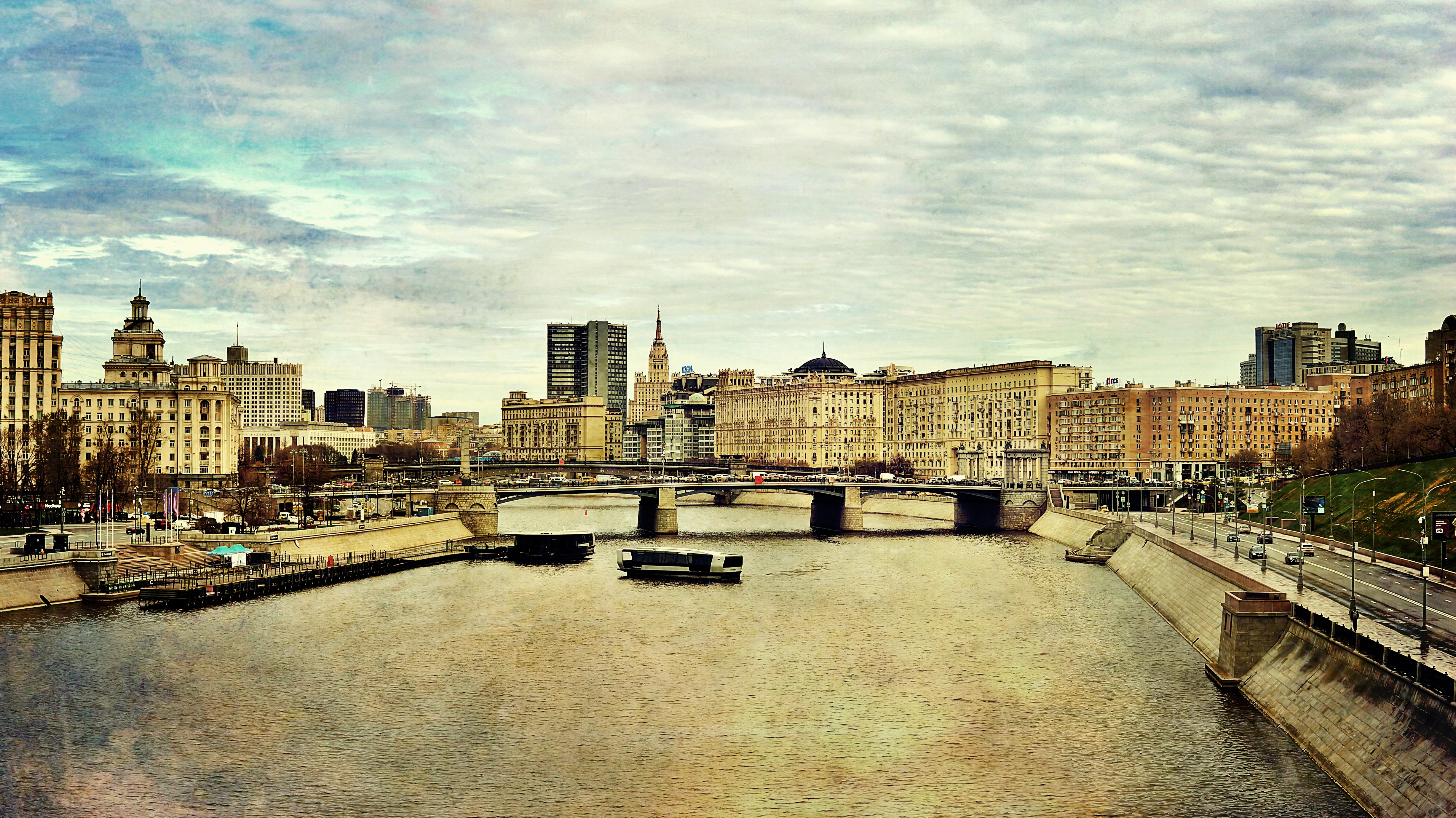 Cityscape with river and bridge under cloudy sky