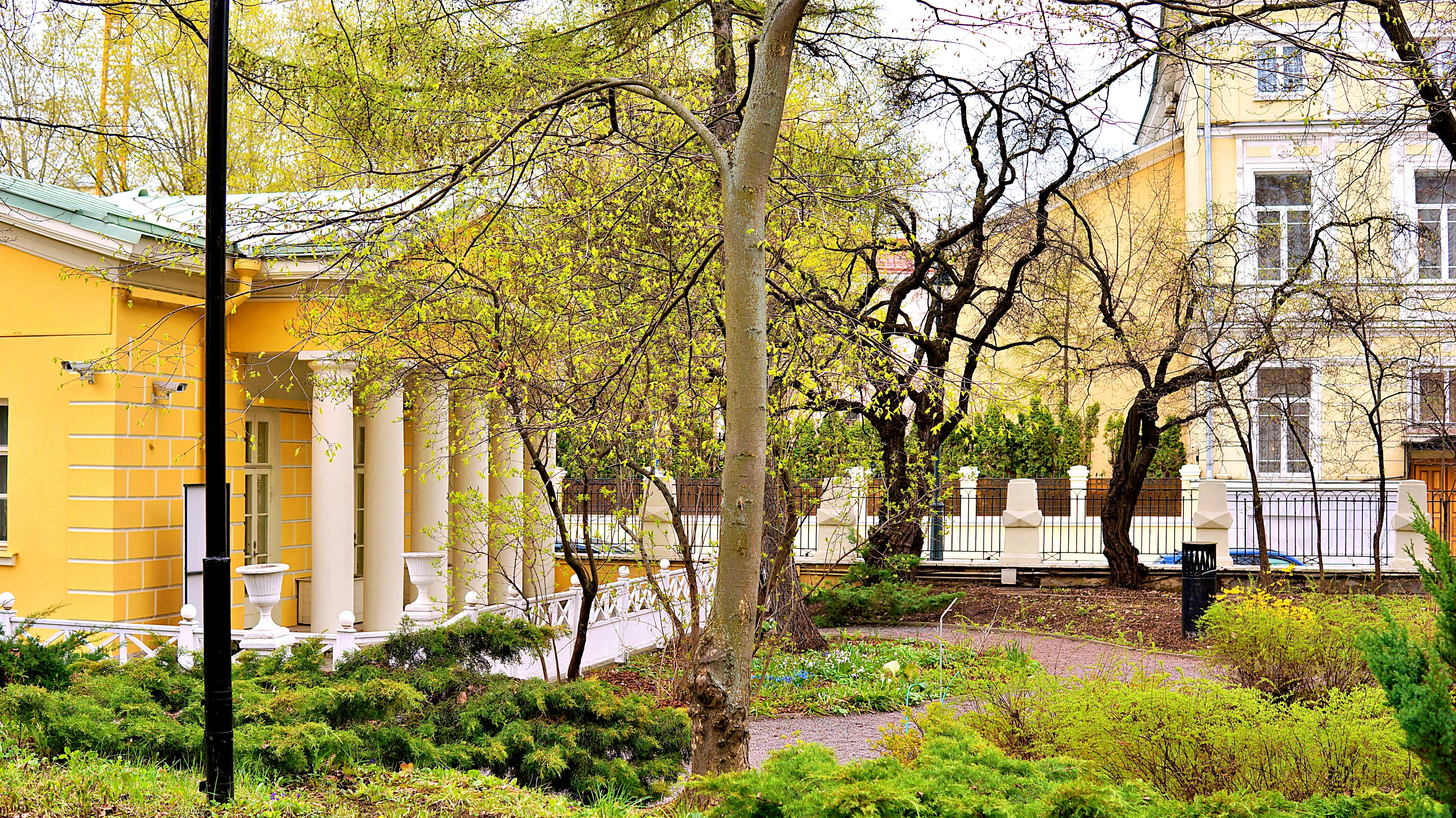 Yellow building with columns and garden in front.