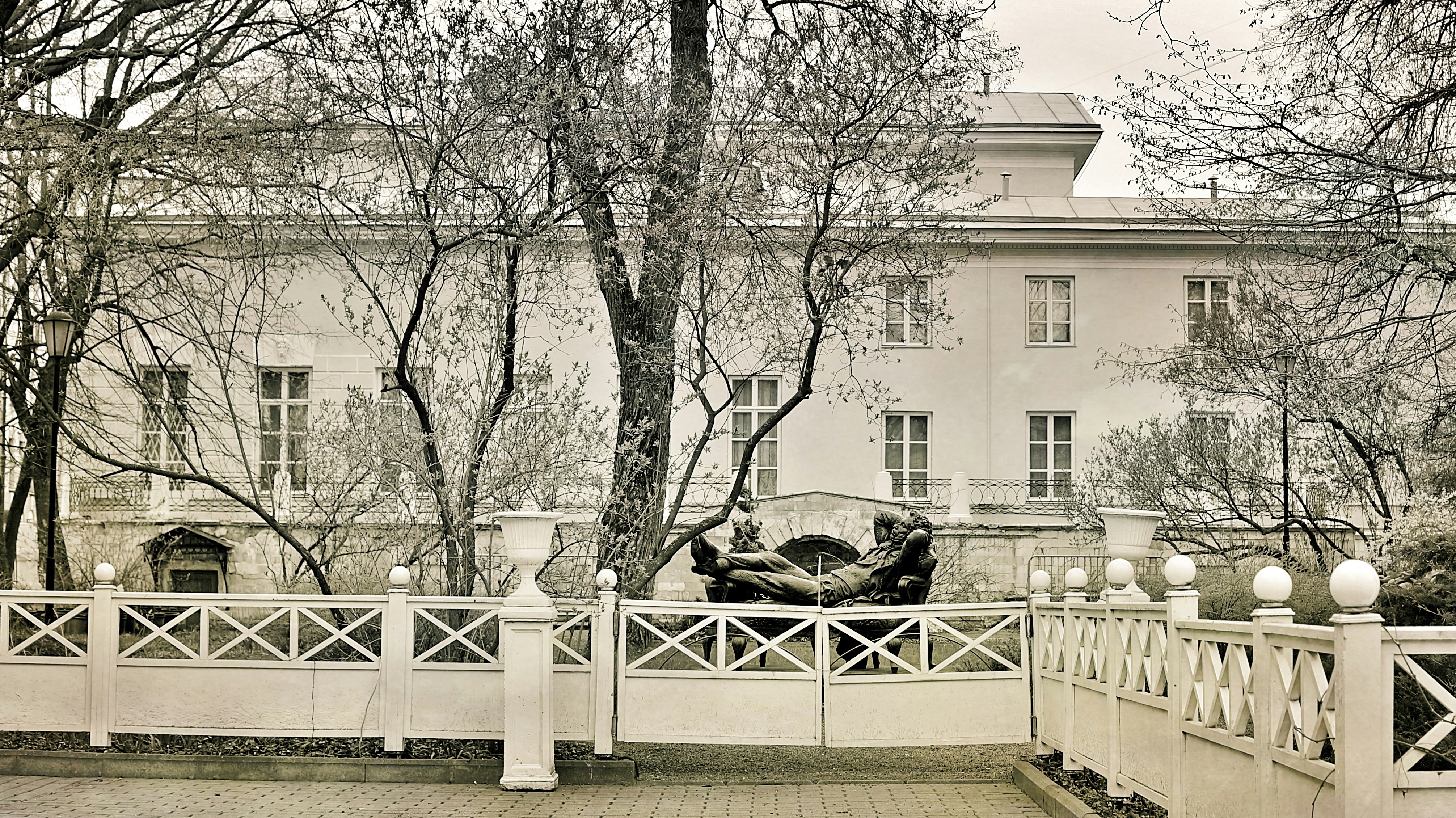 A grand white mansion with ornate fencing and trees.