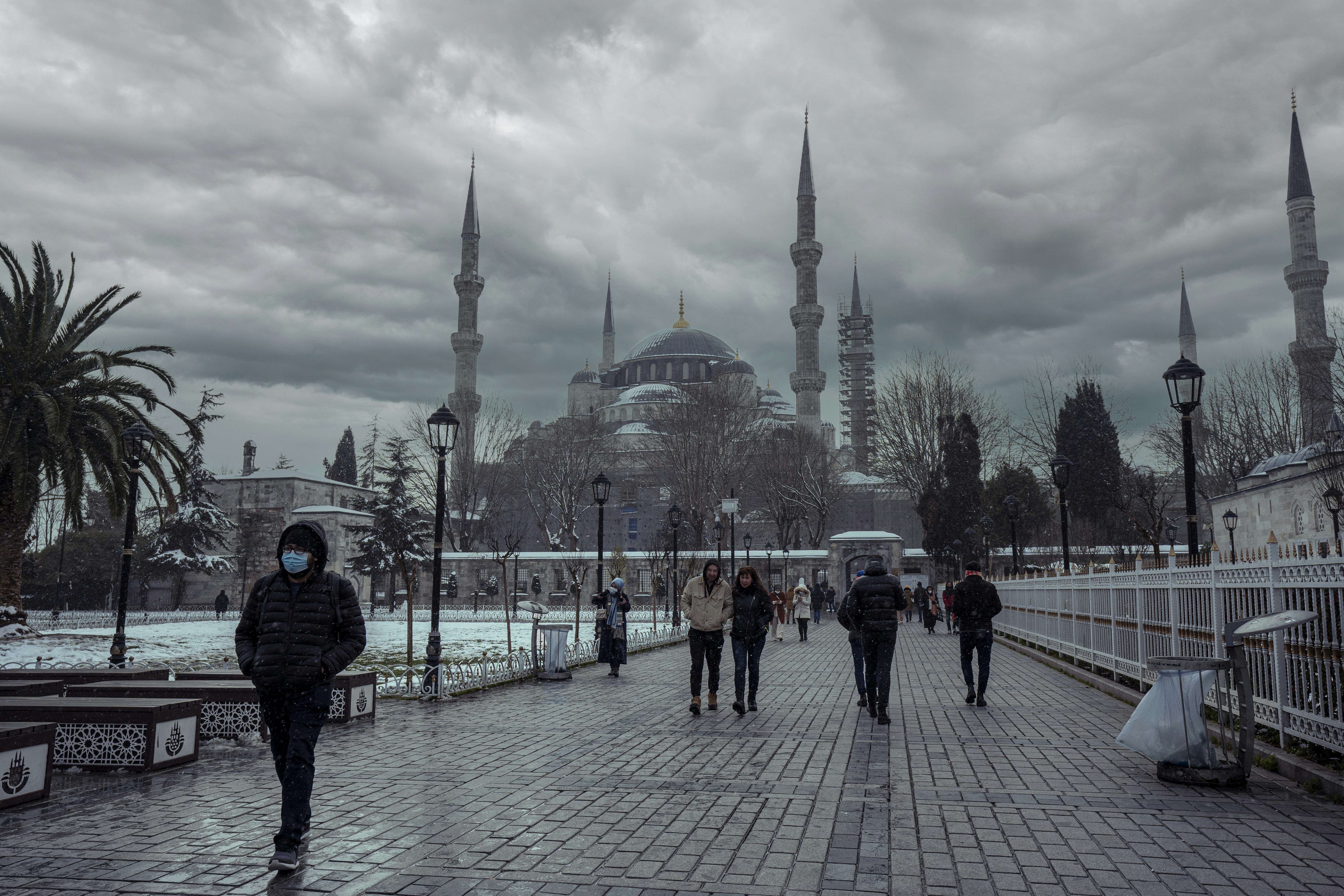 People walk past a mosque on a cloudy day