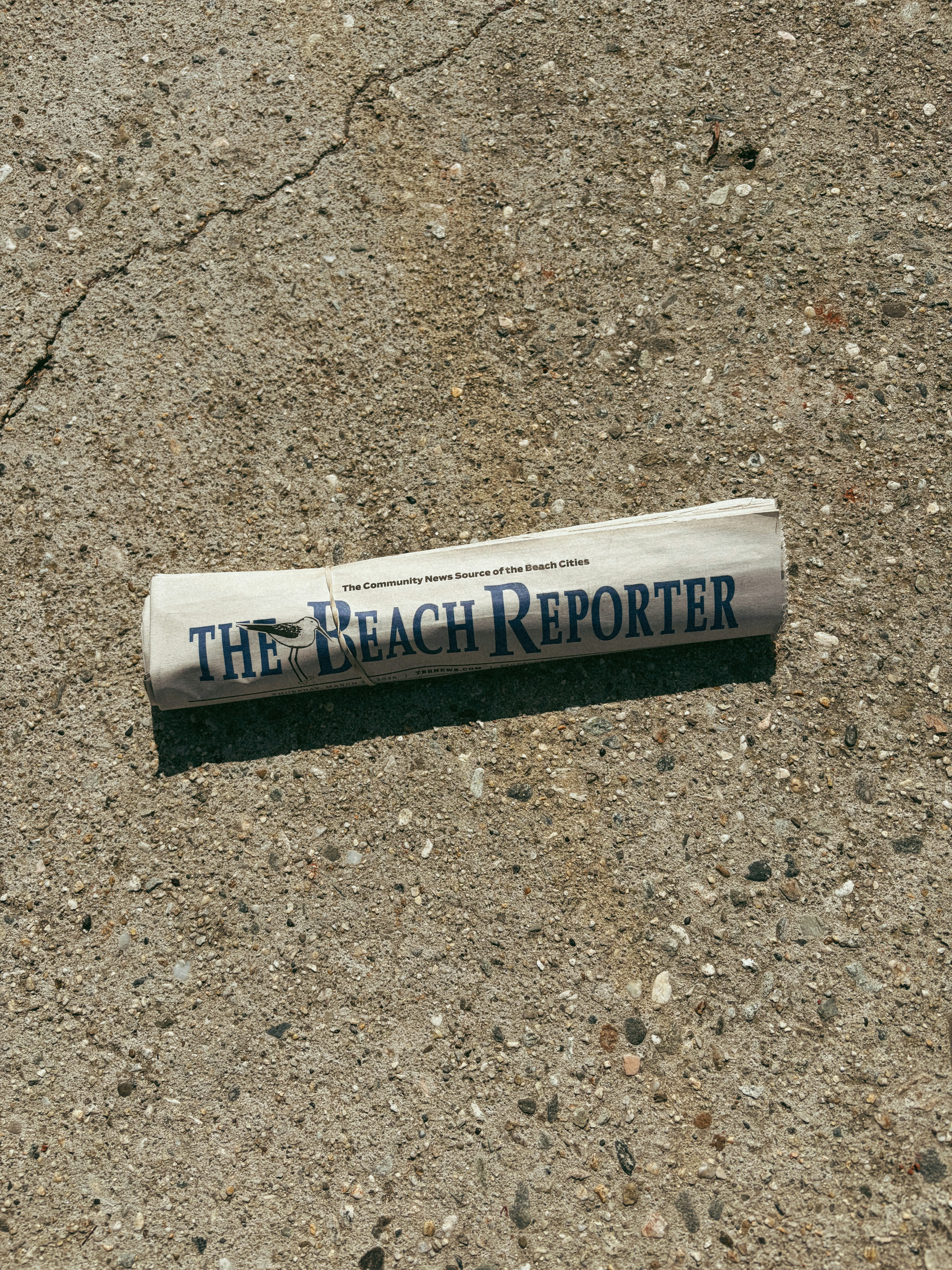 A rolled up newspaper lies on concrete