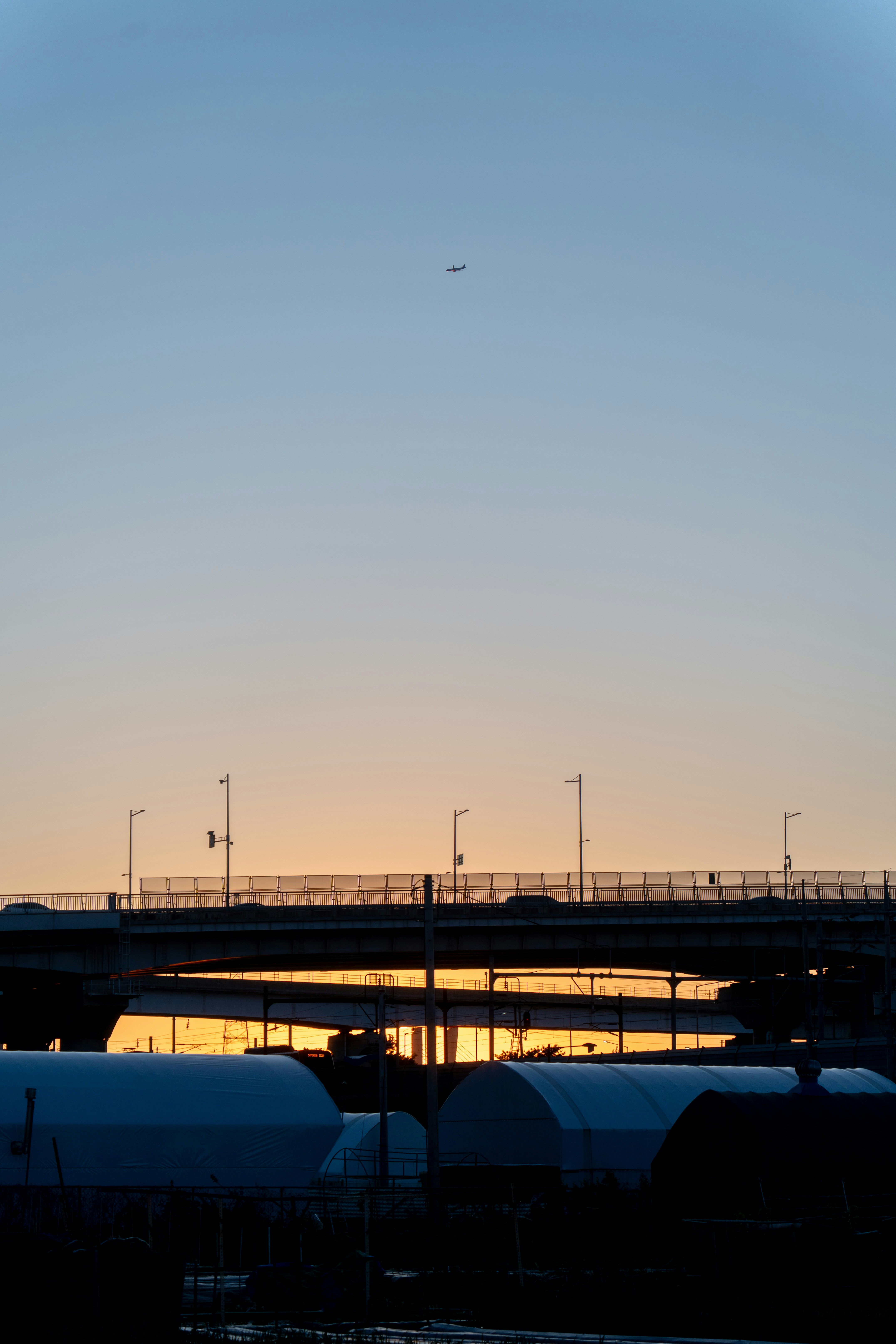 夕暮れ時に橋の上を飛行する飛行機
