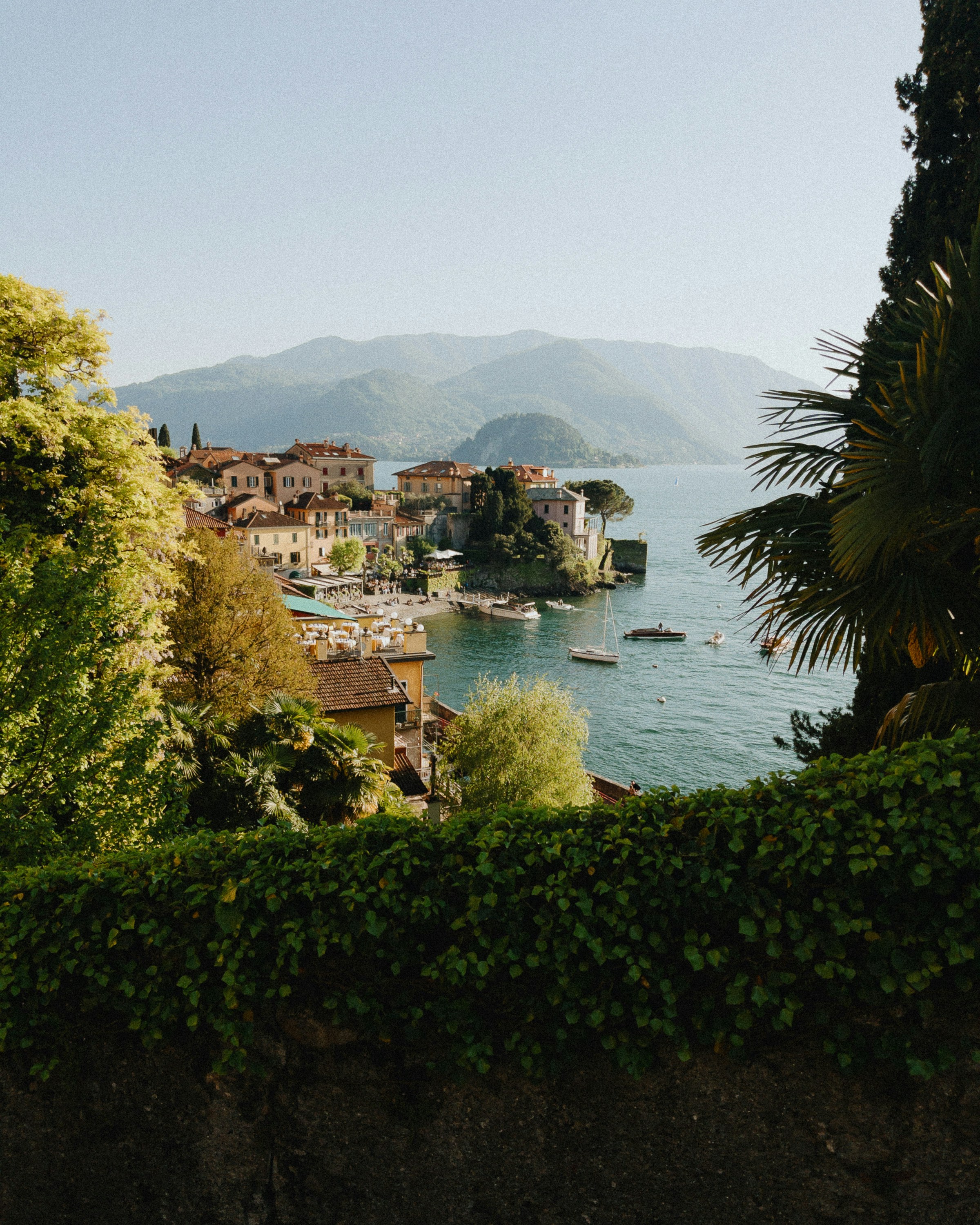 Coastal village with boats on the water and mountains.