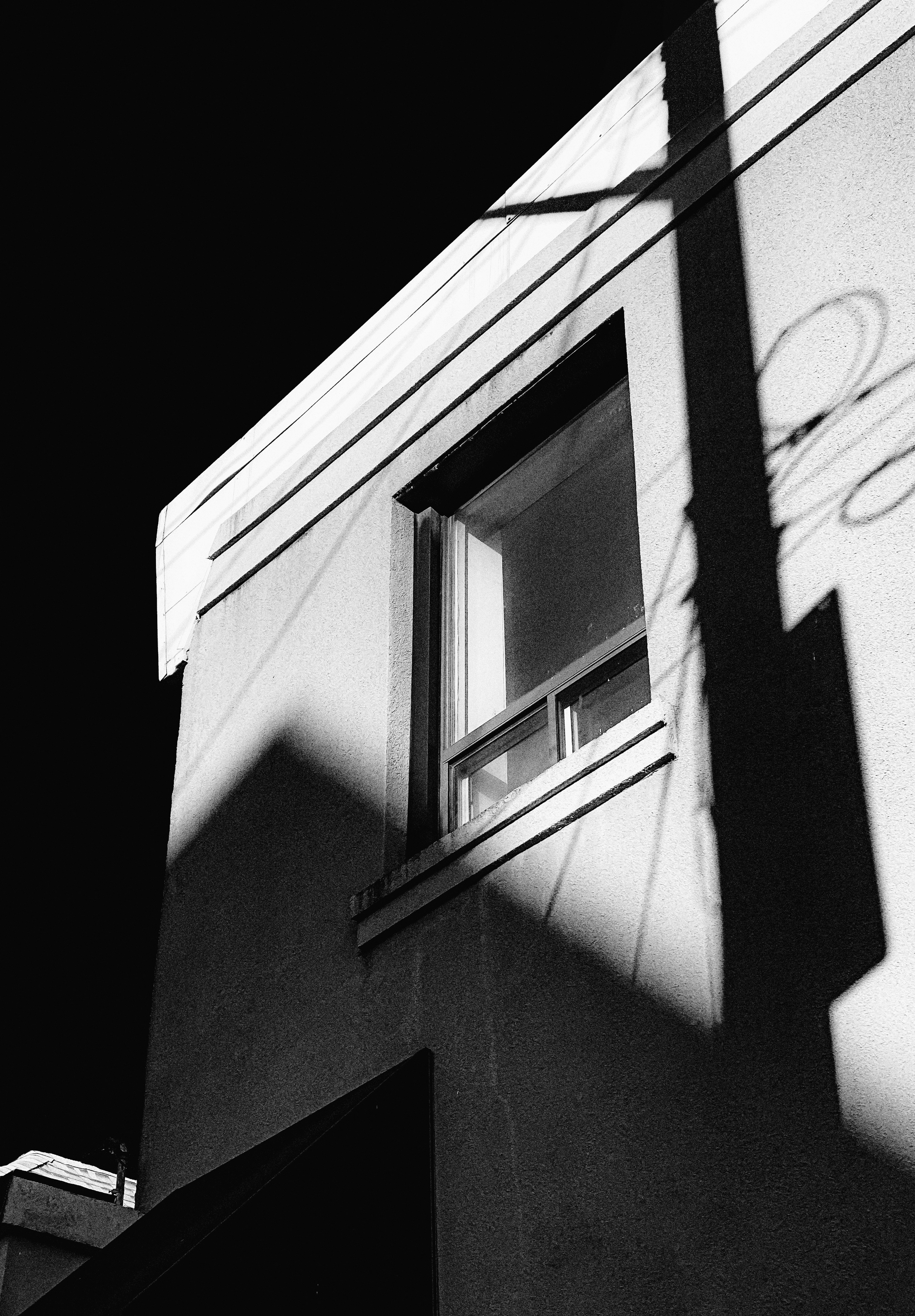 Shadows play on a building's exterior with a window.