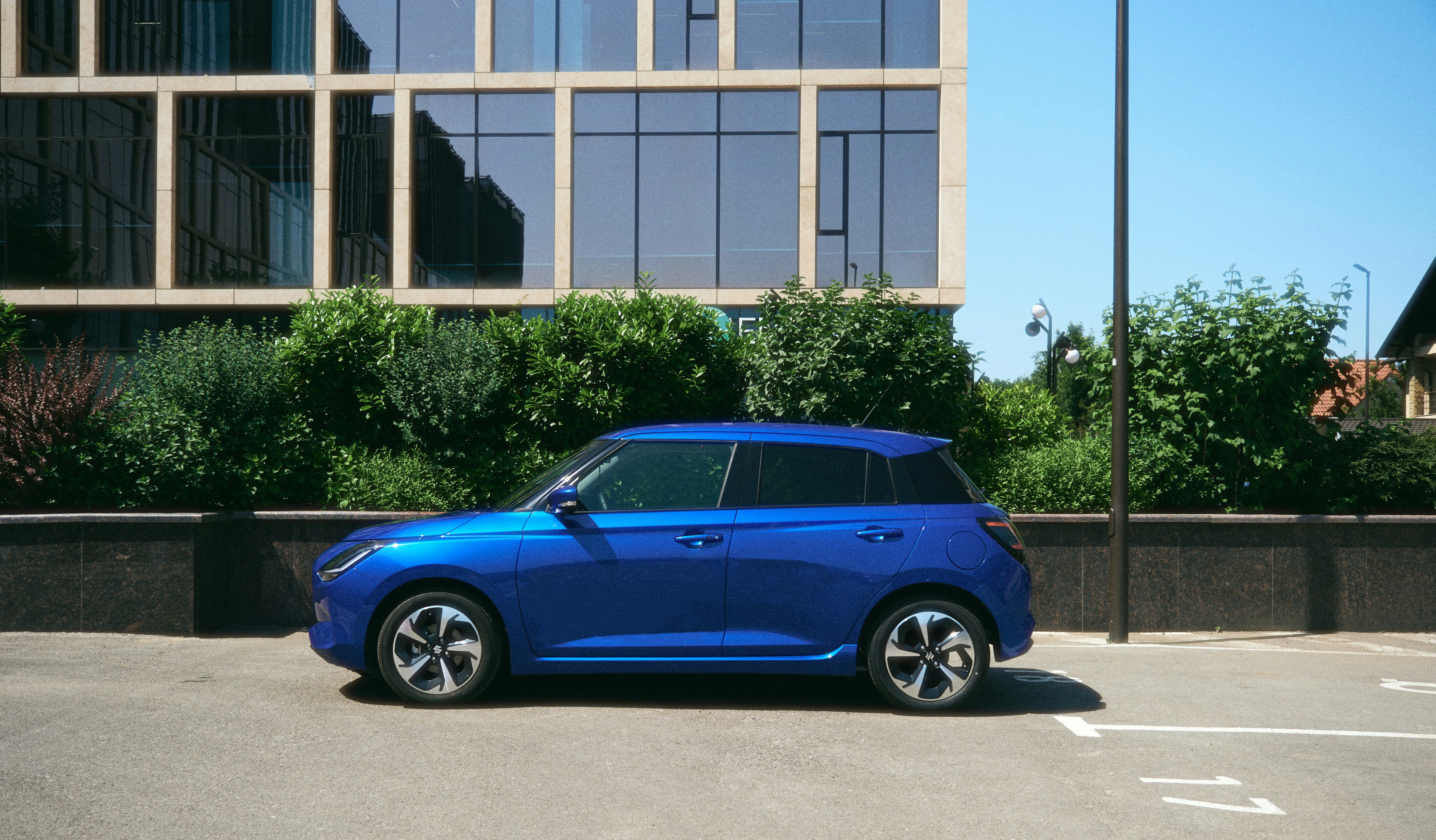 compact electric hatchback car exterior - A blue car parked in front of a modern building.