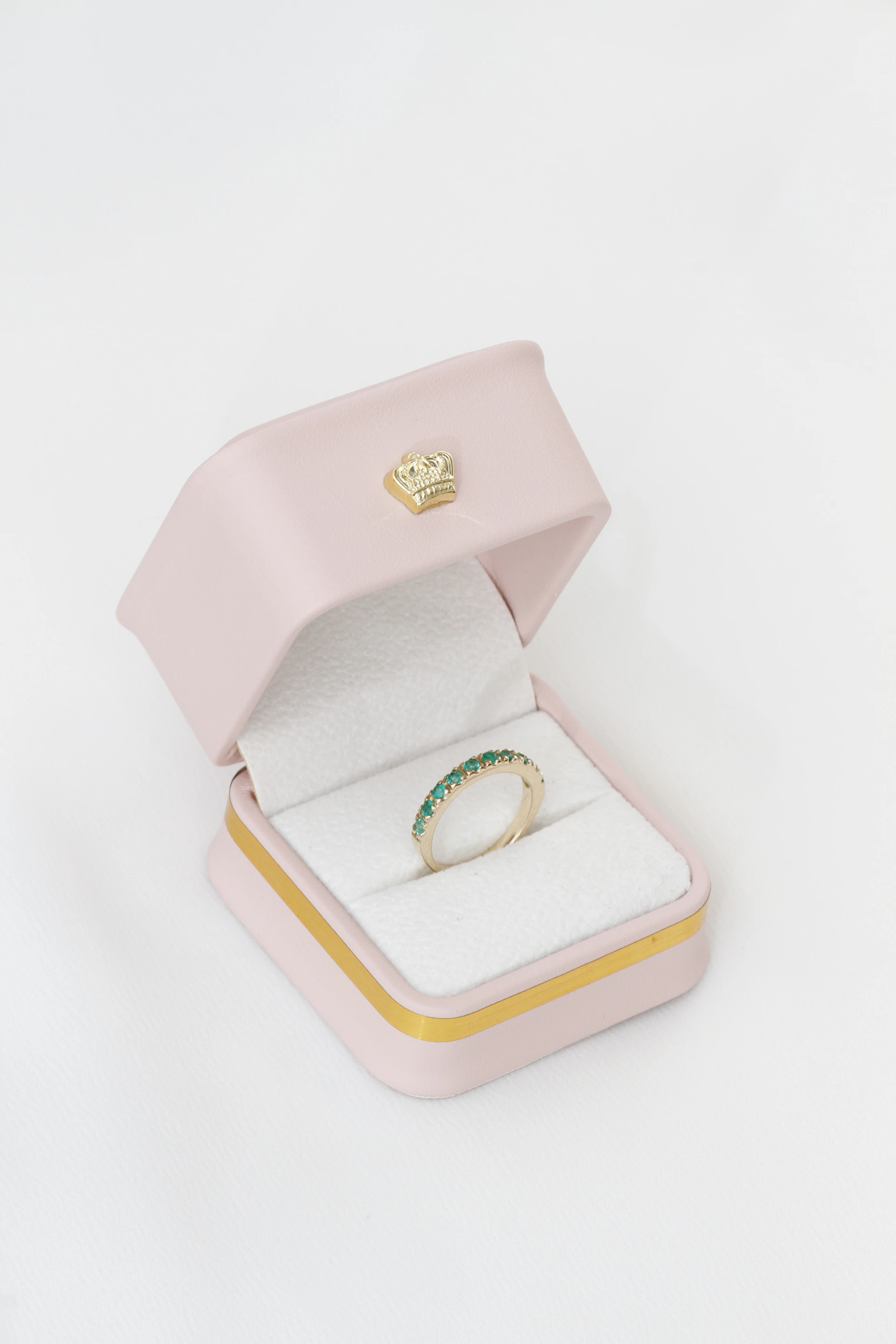 Gold ring with green gems in a pink box