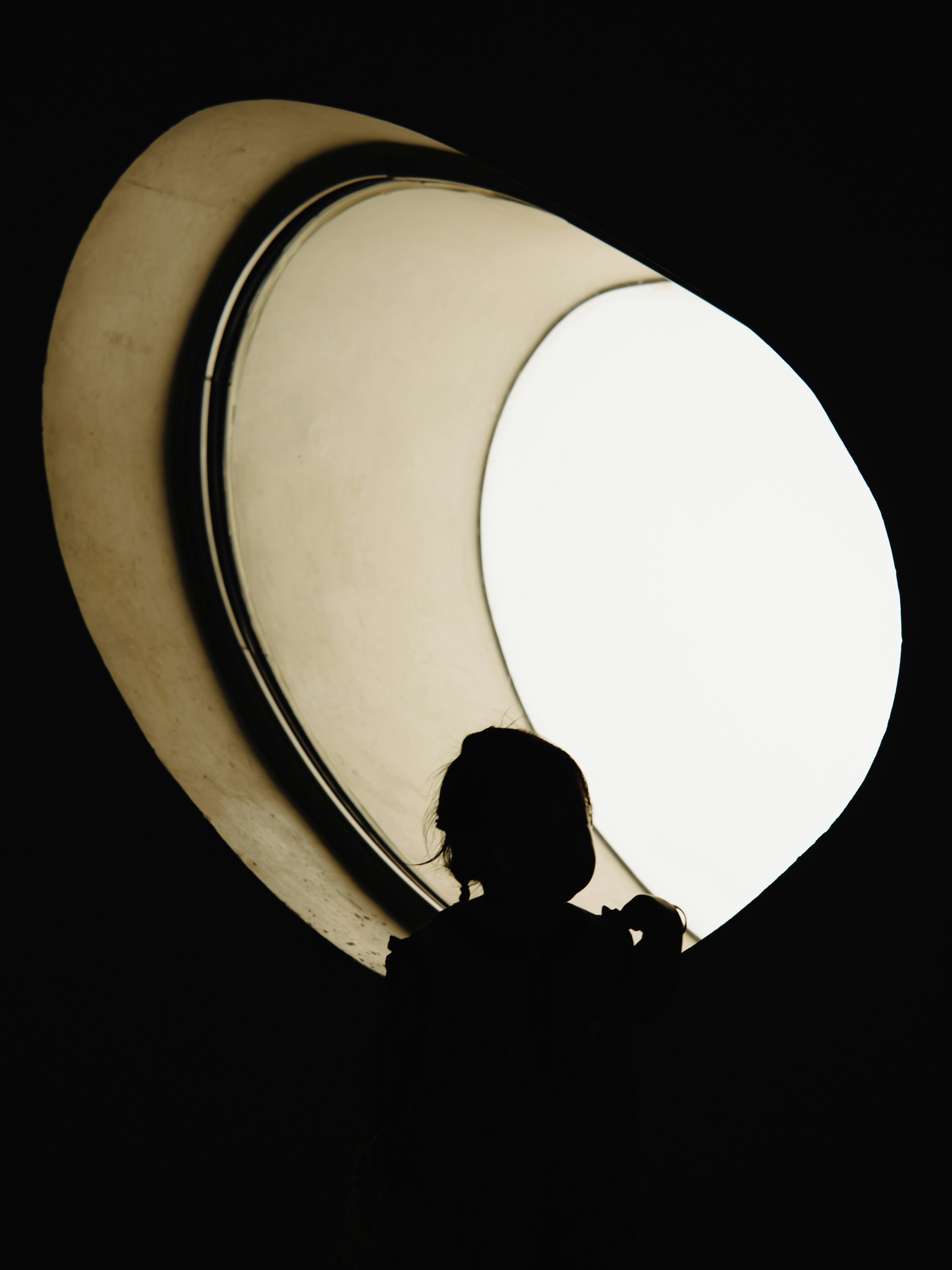 Silhouette of a person looking out a large window.