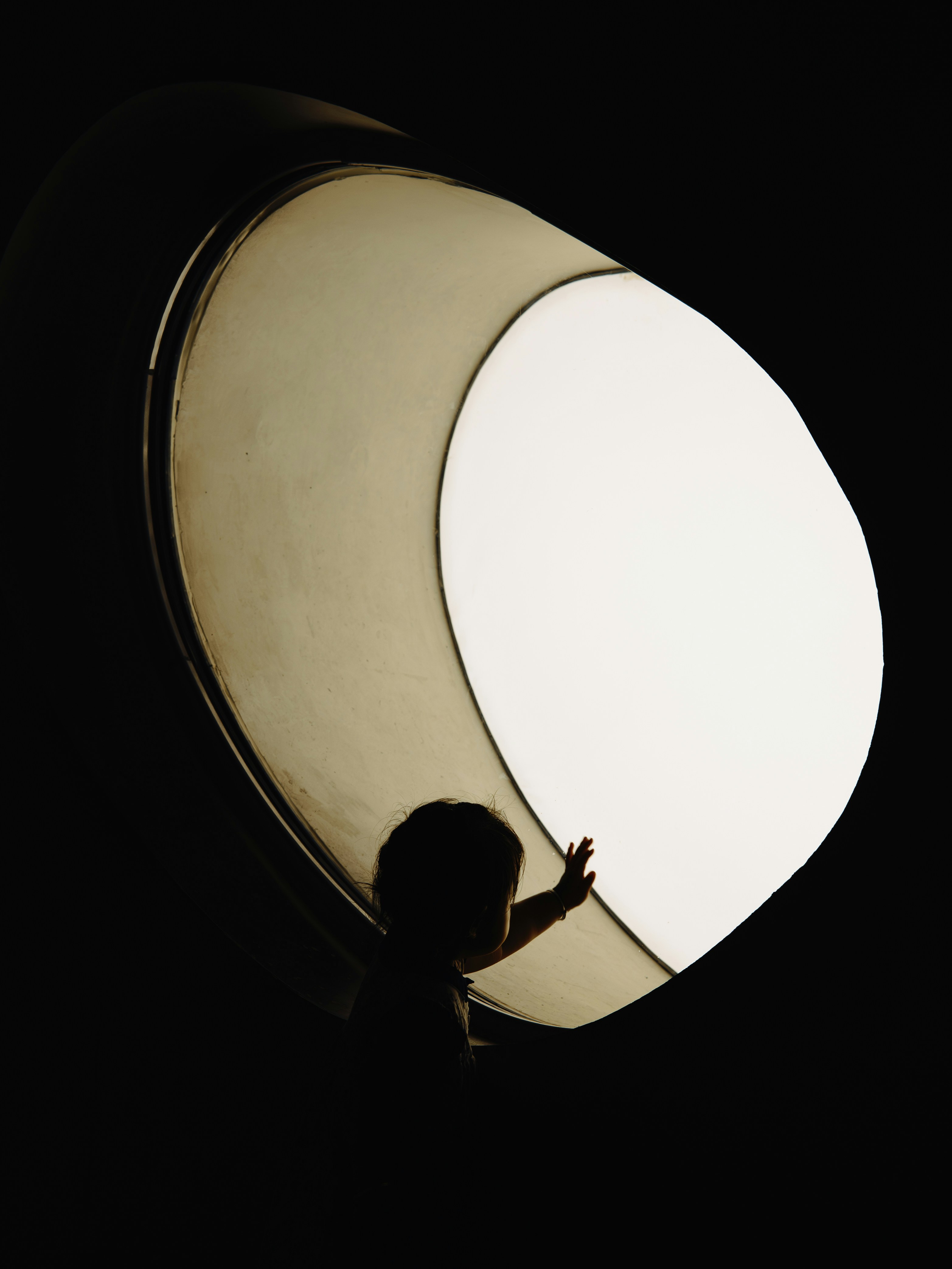 Silhouette of a child reaching towards a bright light.
