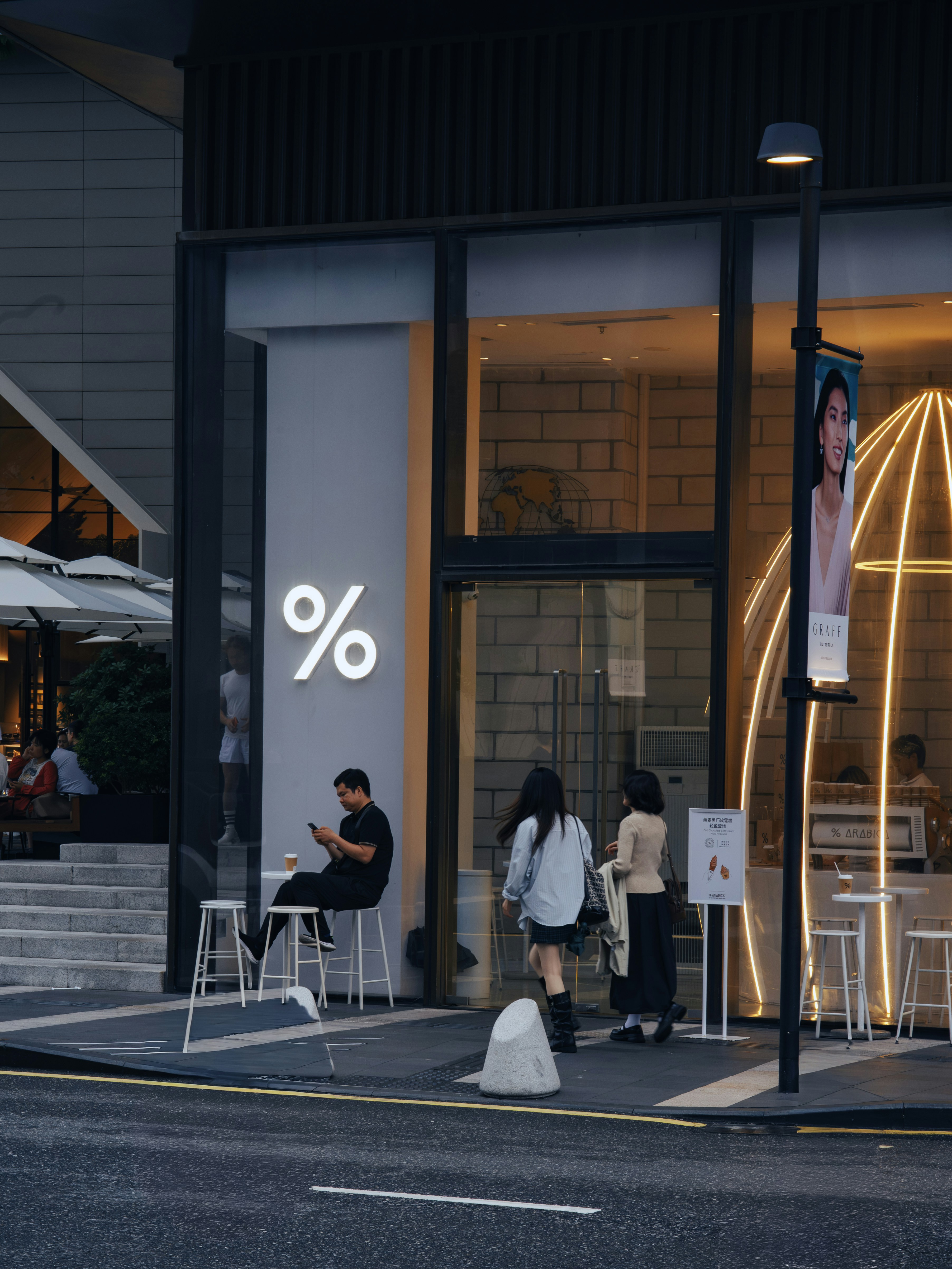 People outside a modern coffee shop with a % logo