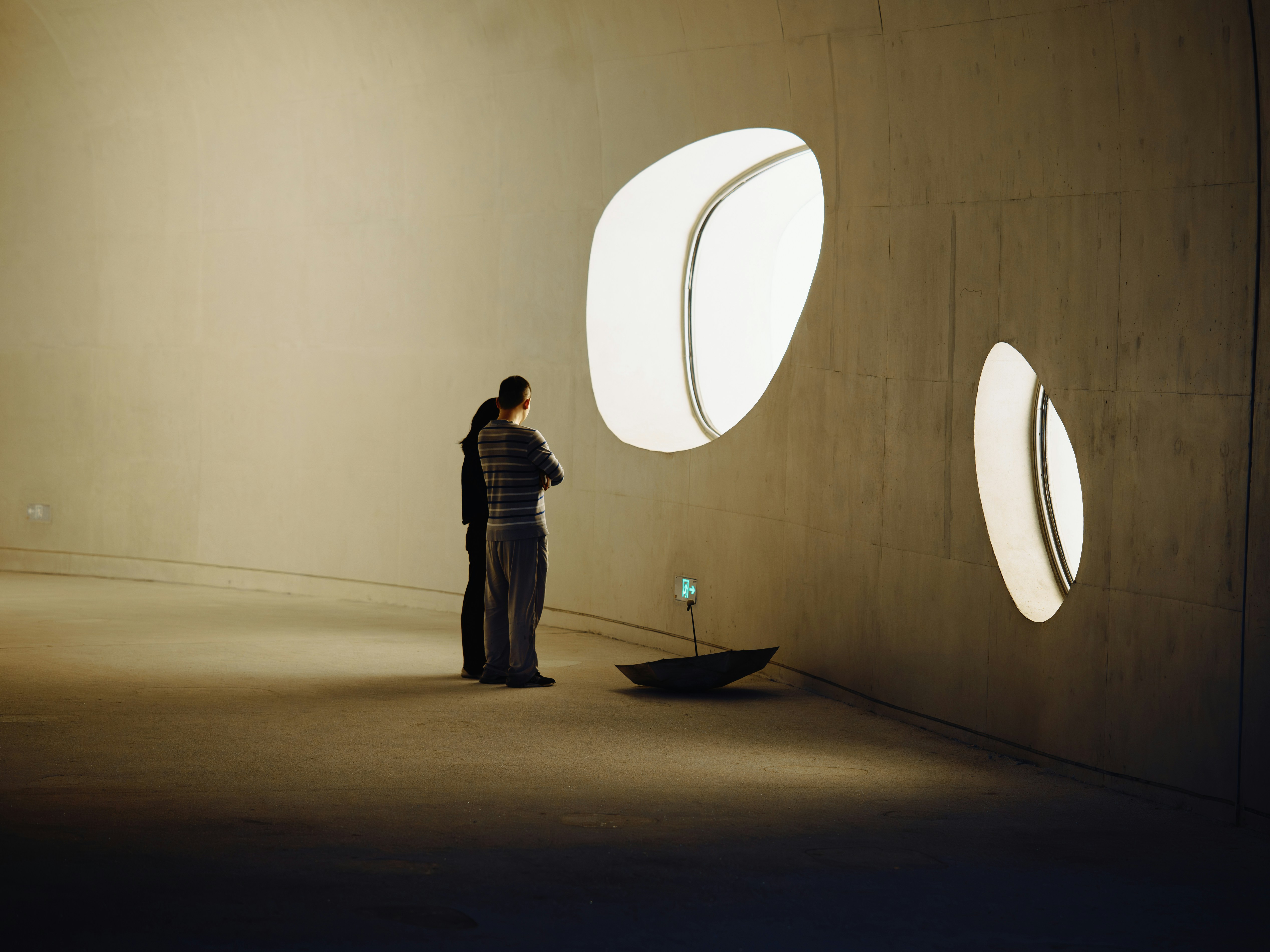 Two people stand in a modern room with abstract windows.