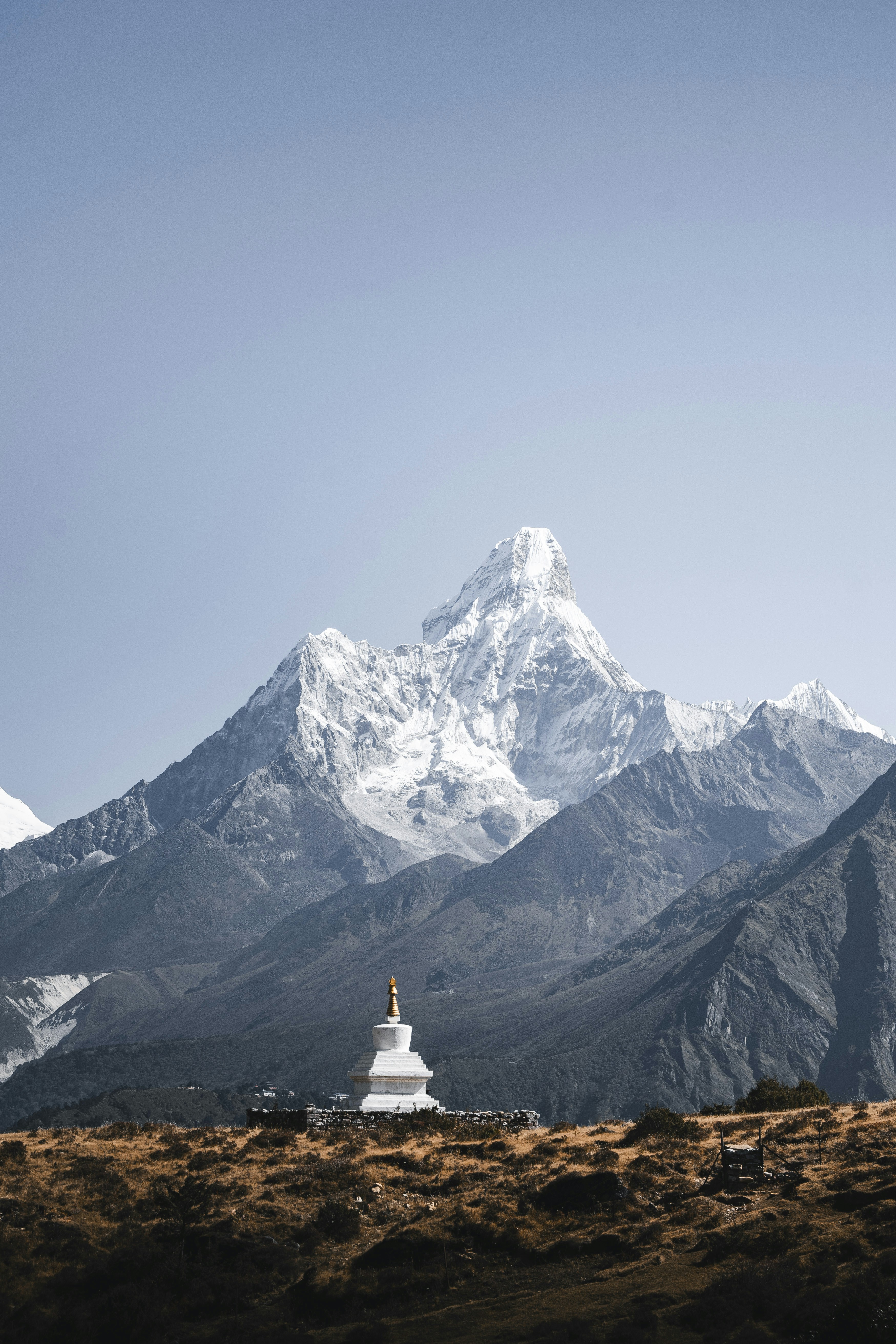 Uno stupa bianco si erge davanti a una maestosa montagna innevata.