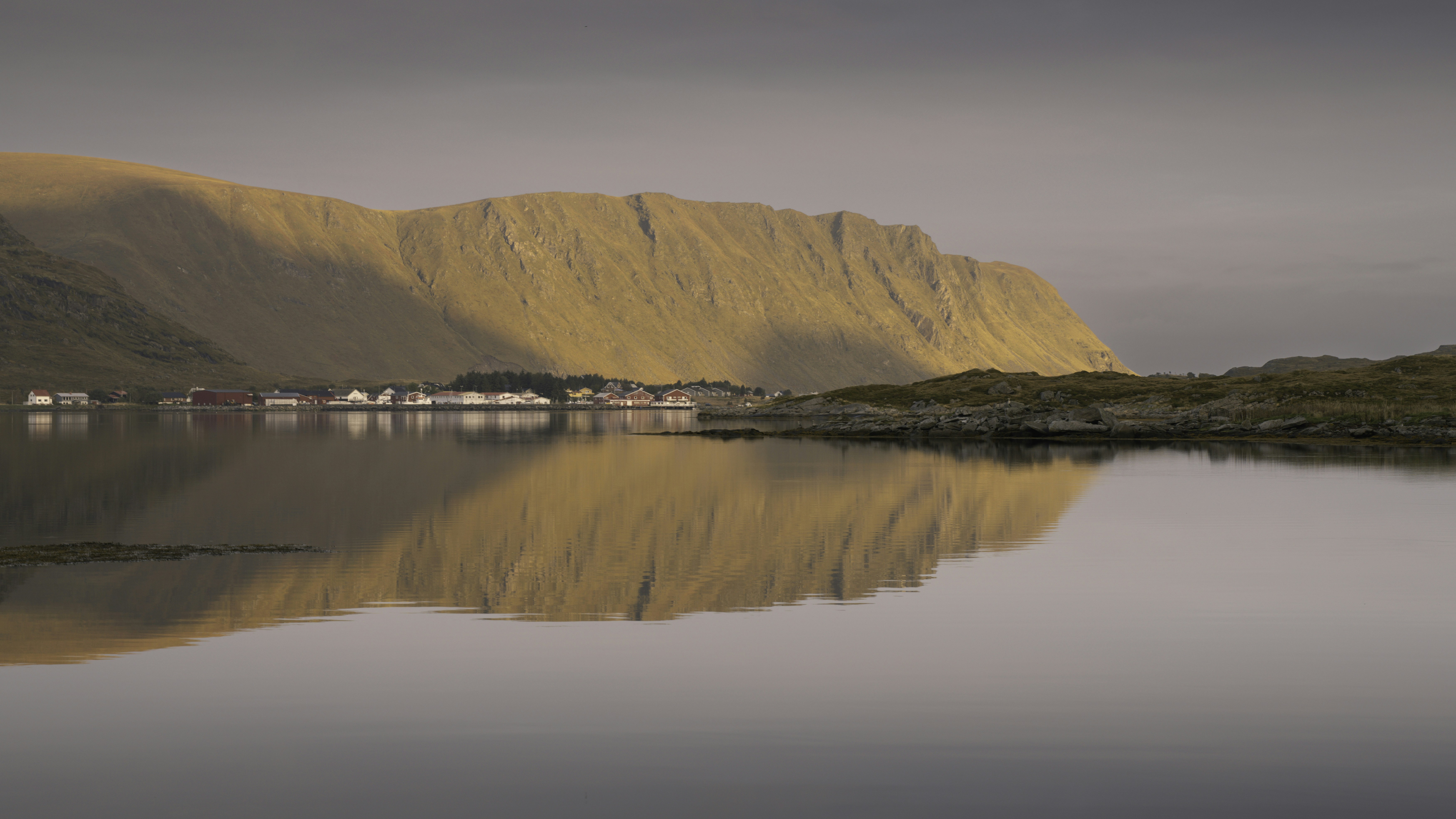 Pueblo costero con reflejo de montaña en aguas tranquilas