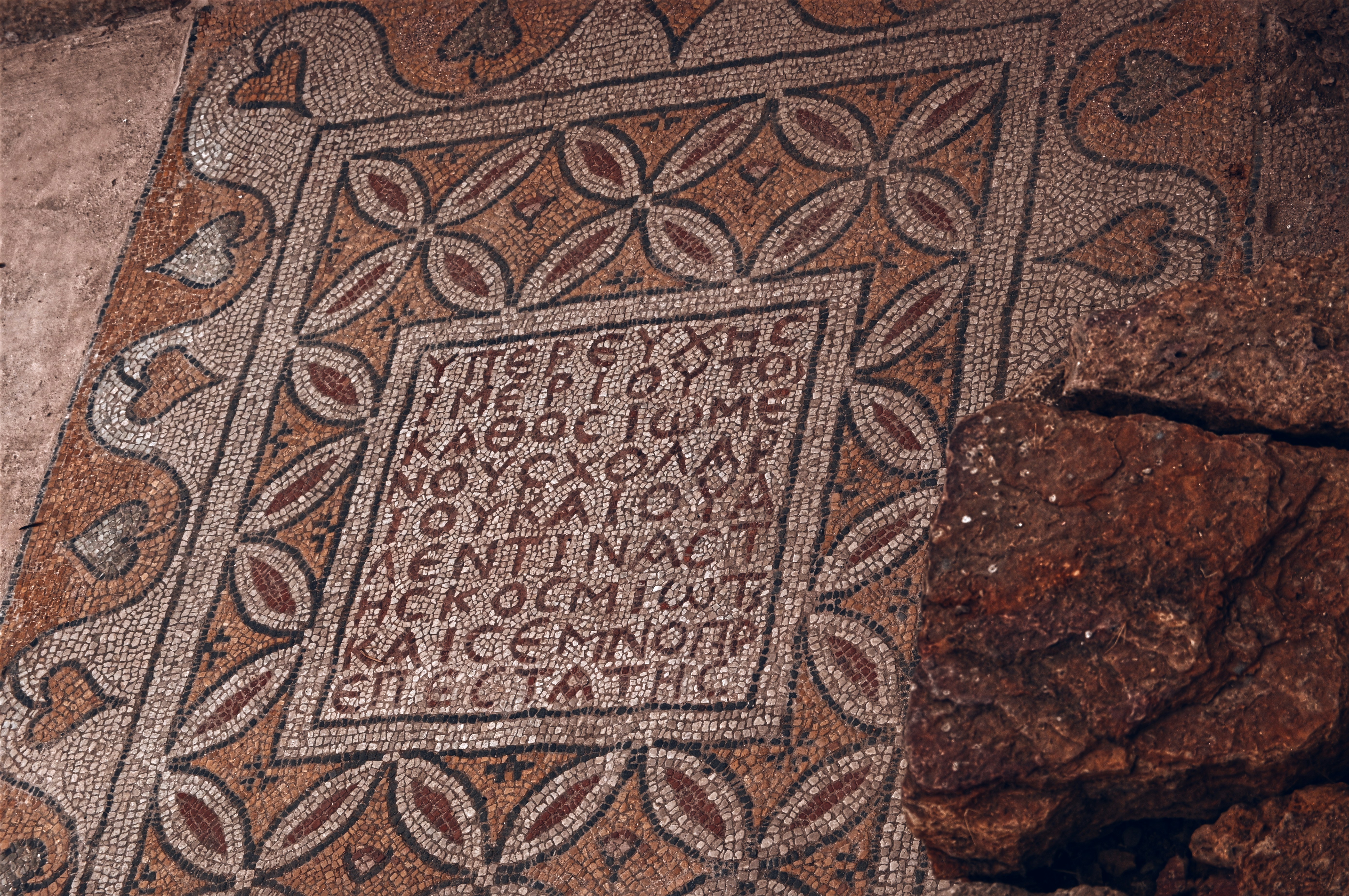 Mosaico antigo com inscrição grega e padrão floral