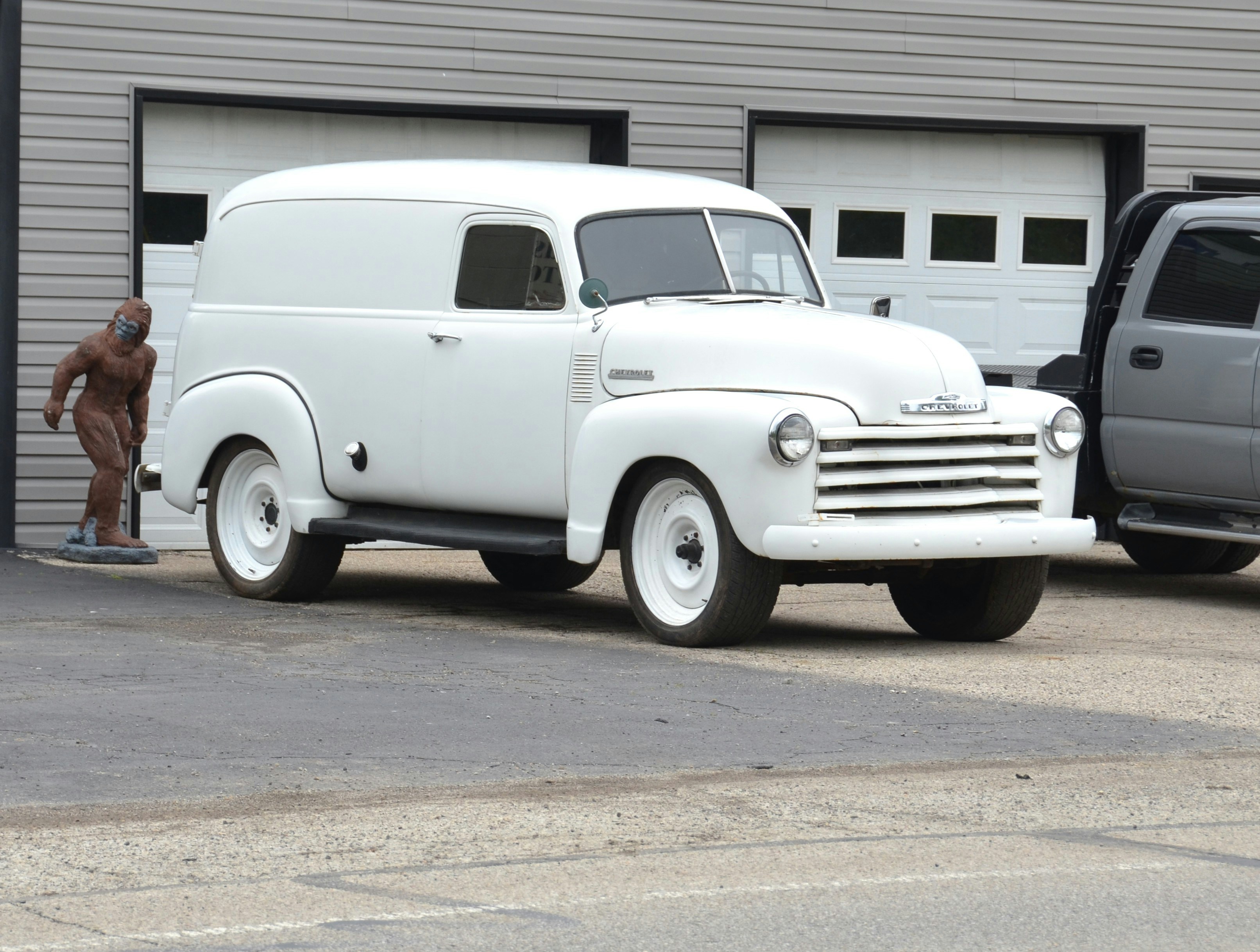 Un fourgon blanc vintage garé devant un garage.