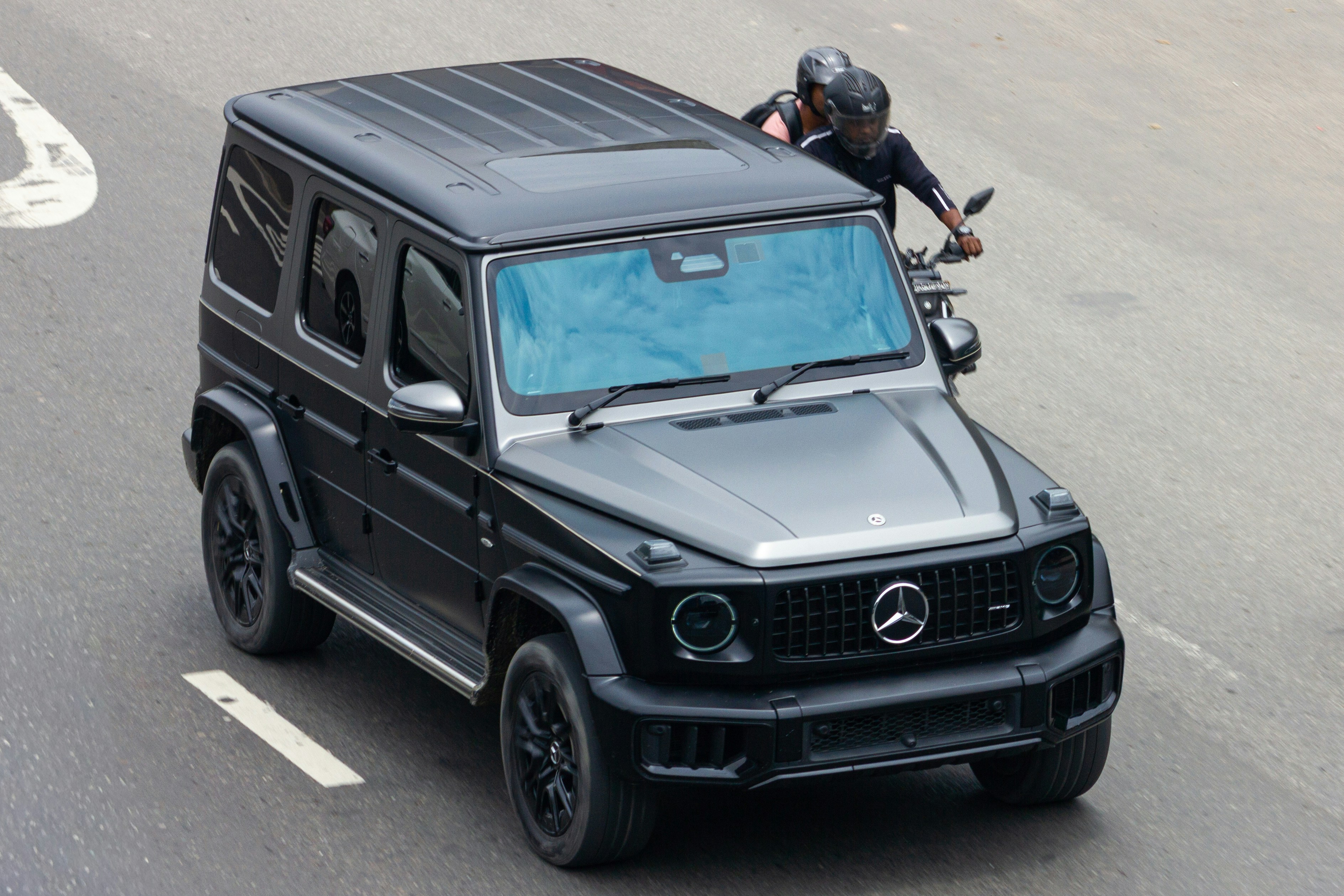 Black mercedes g-wagon driving on a road with motorcycle