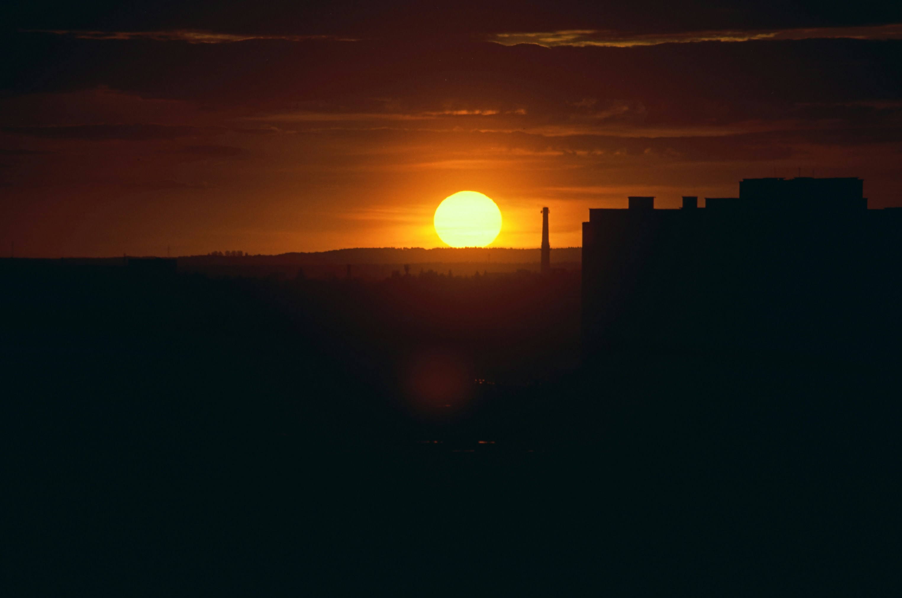 Sunset over a silhouetted cityscape with buildings.