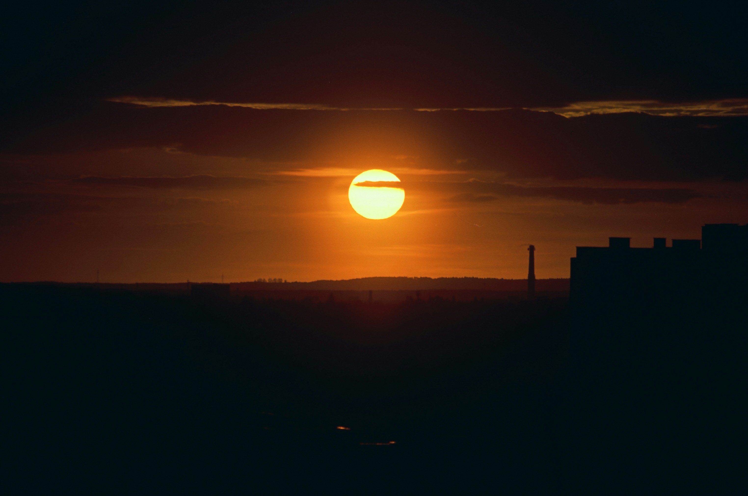 The sun setting over a dark cityscape.