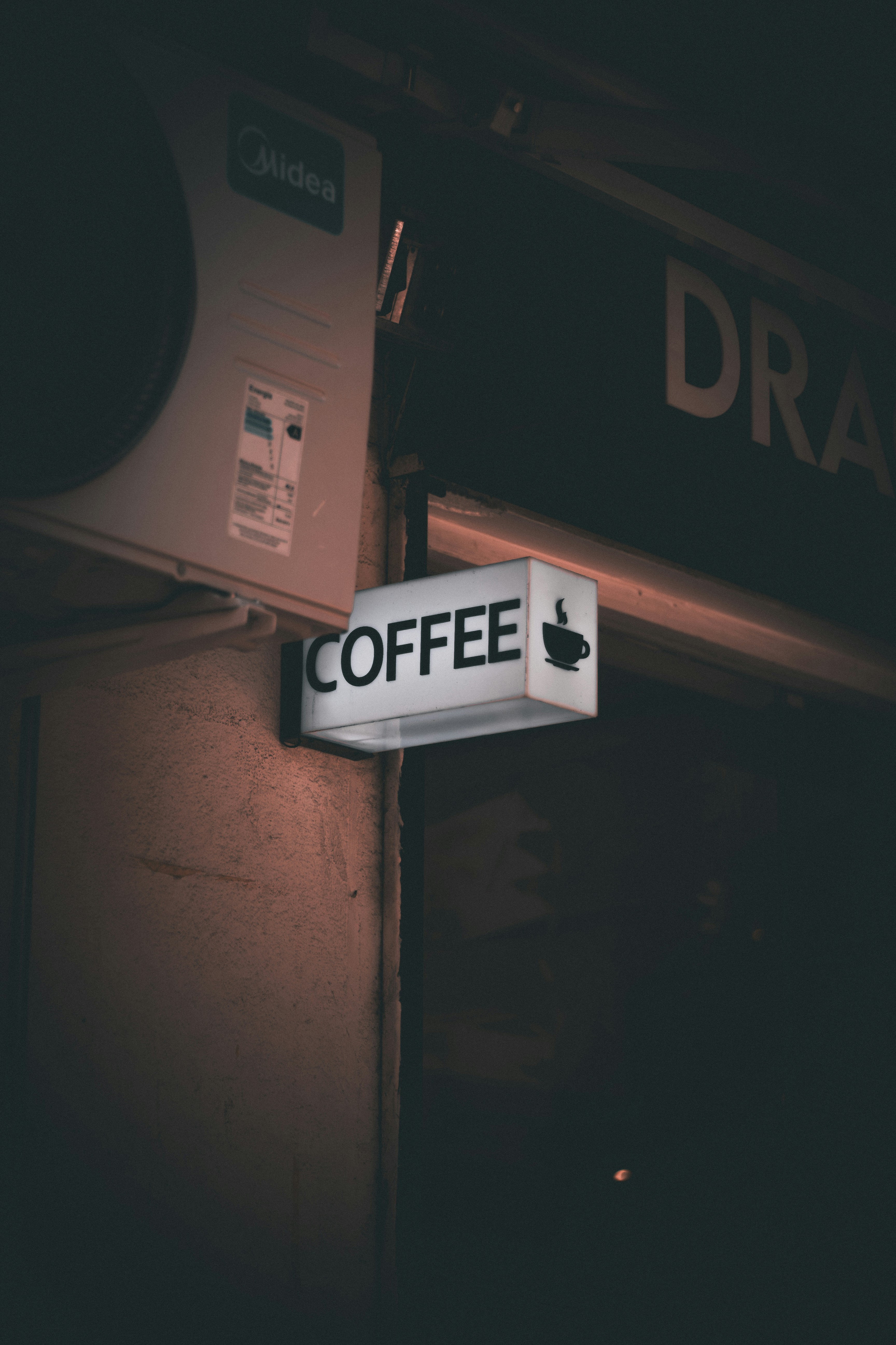 Beleuchtetes Kaffeeschild an einem Gebäude bei Nacht