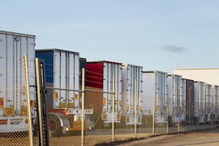 Row of parked semi-trailer trucks behind a fence