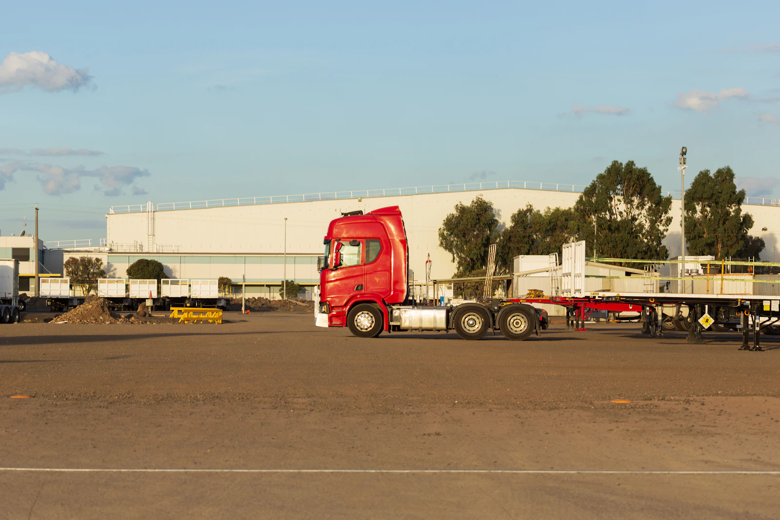 Red semi-truck parked at industrial lot