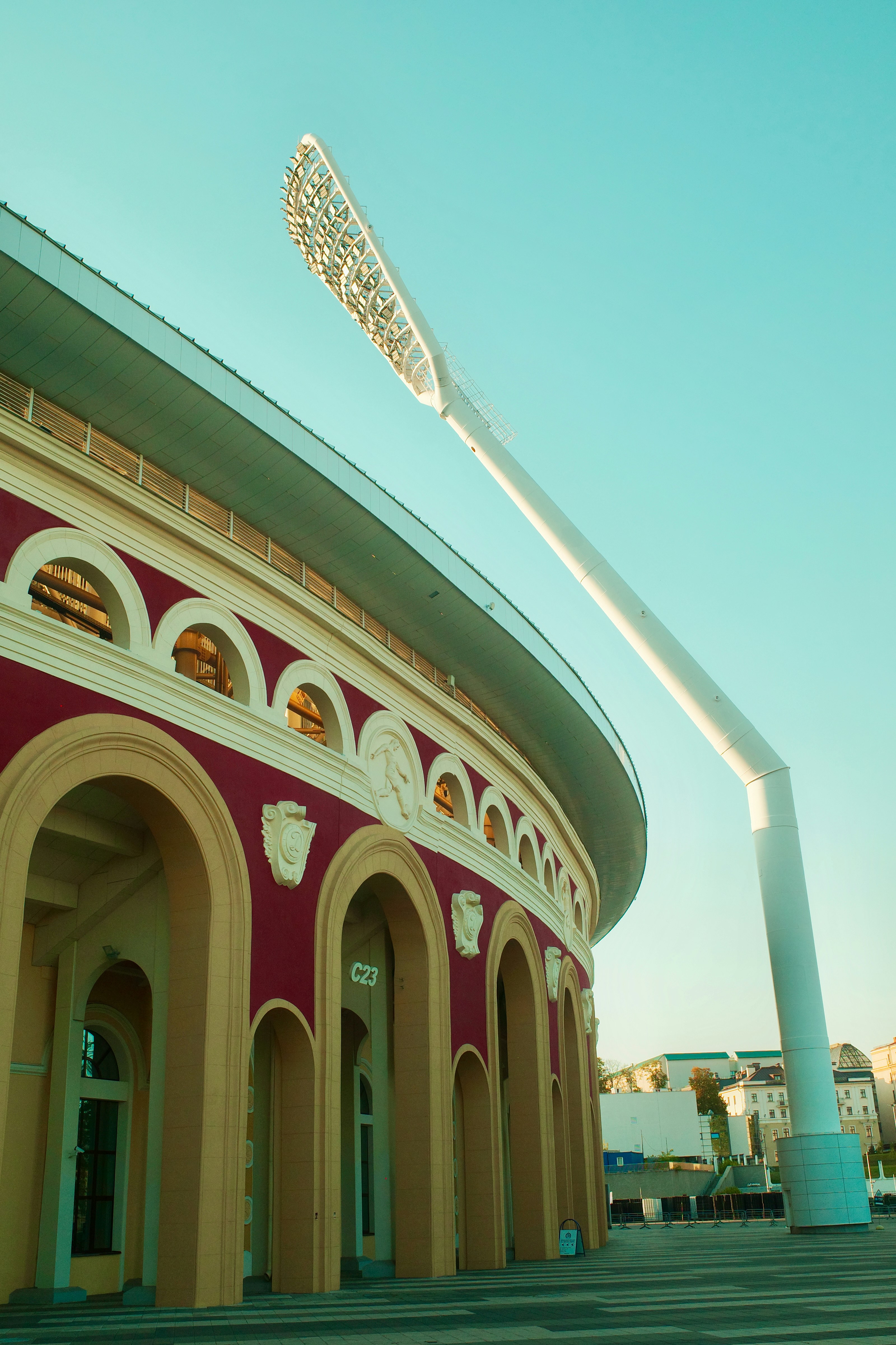 Modern stadium architecture with arched entrances and tall light tower