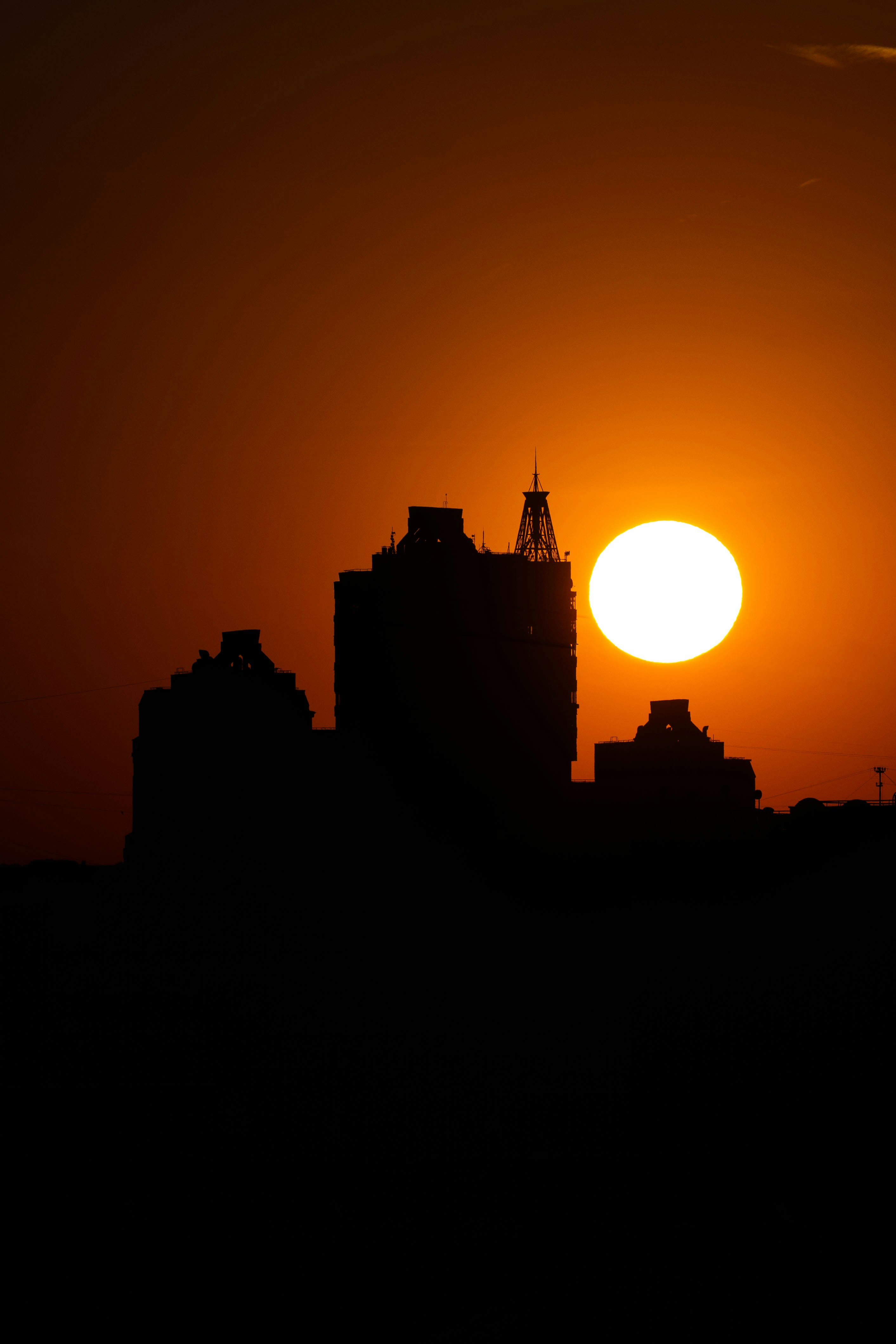 Silhouetted buildings against a bright orange sunset