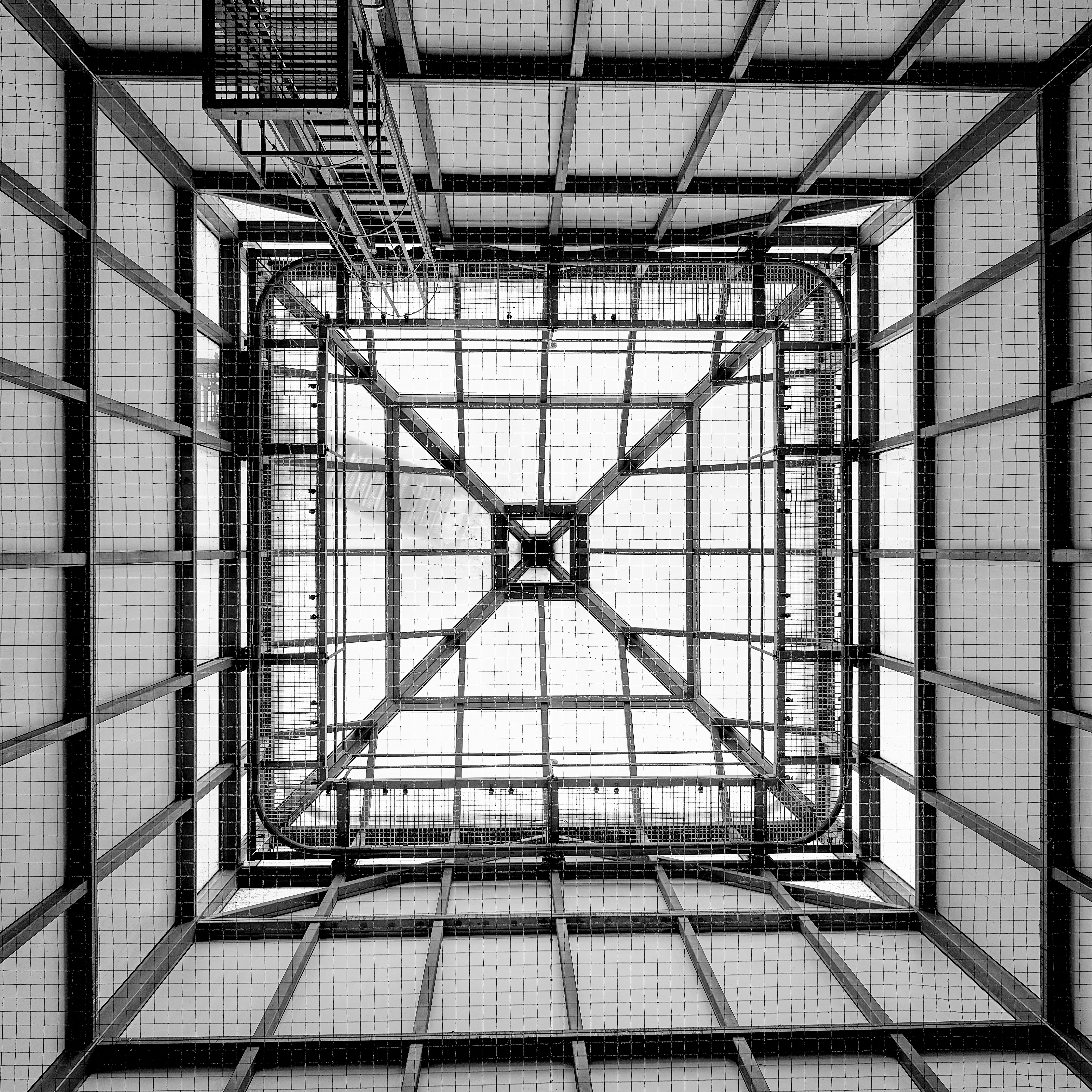 Looking up through a geometric metal structure towards sky