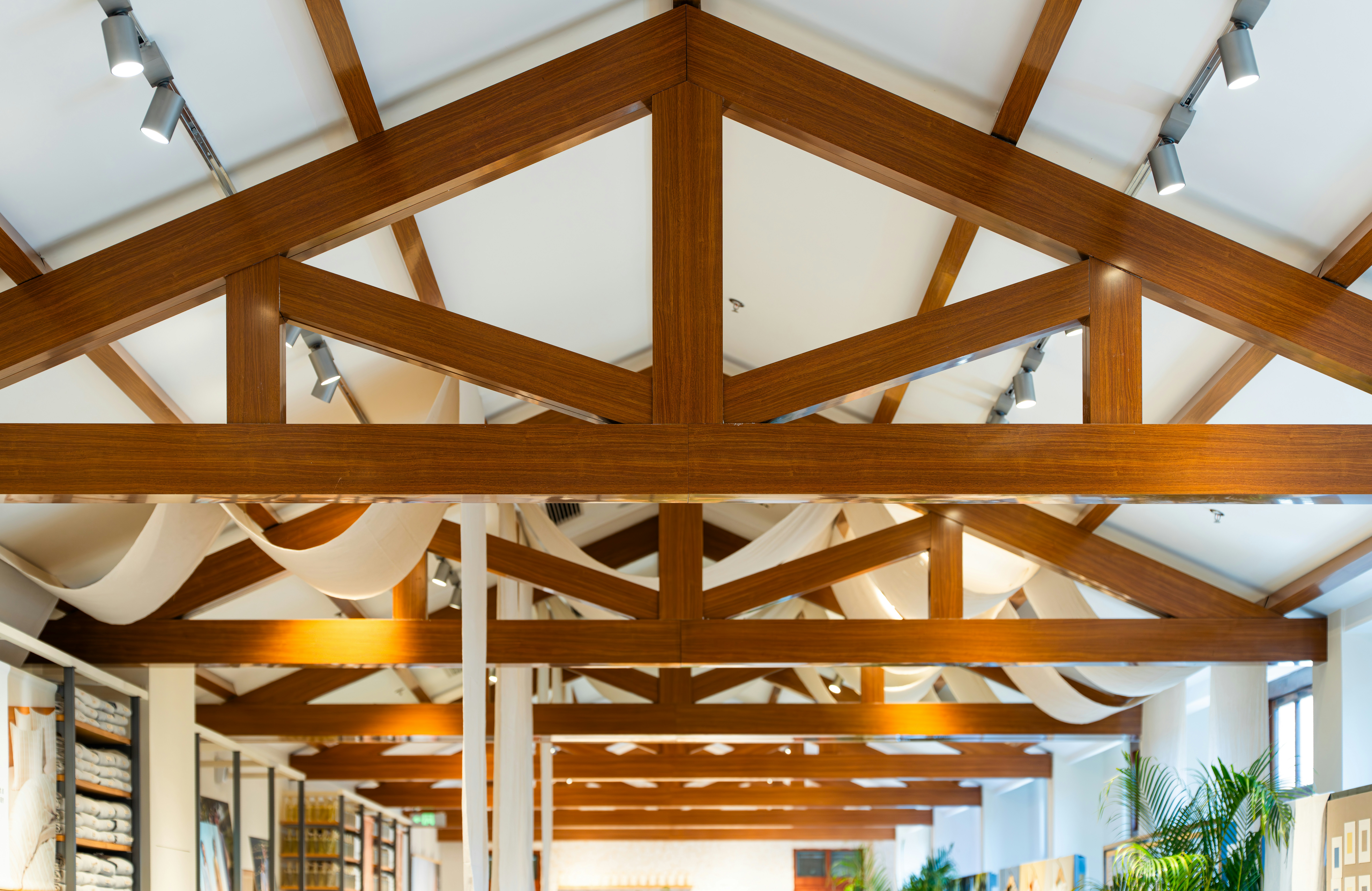 Wooden roof beams with modern lighting and fabric accents.