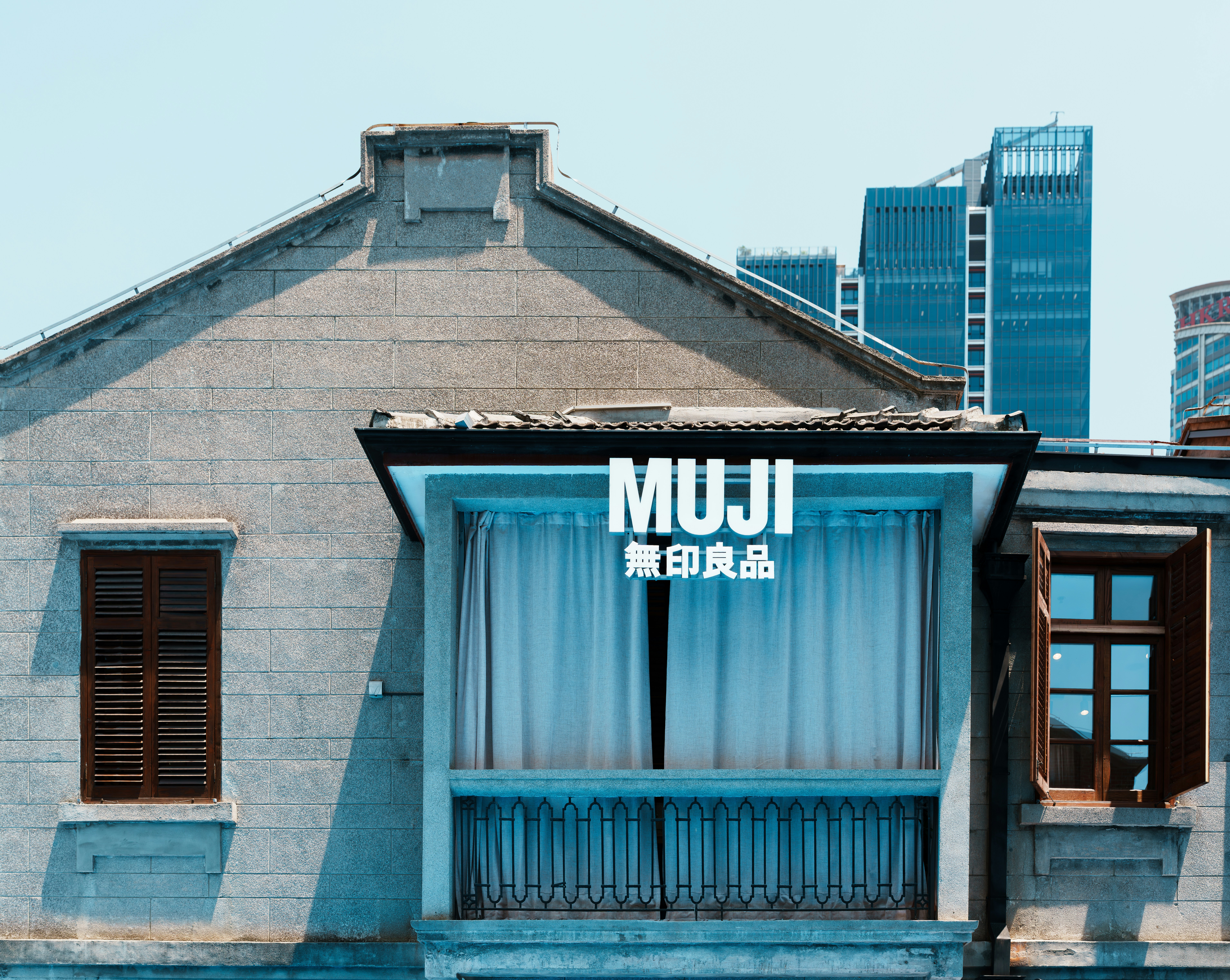 Muji store facade with modern buildings behind old building