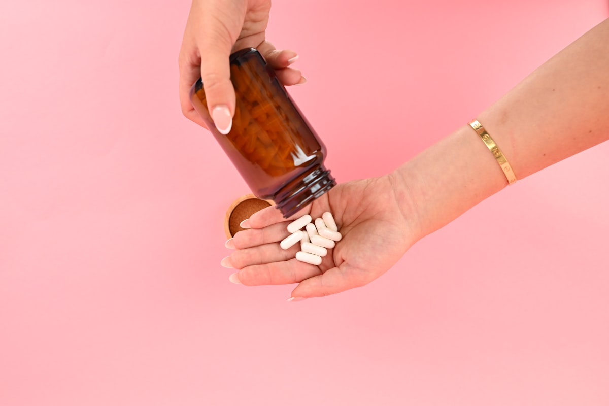 Someone pouring capsules from a plain, unbranded bottle into their hand