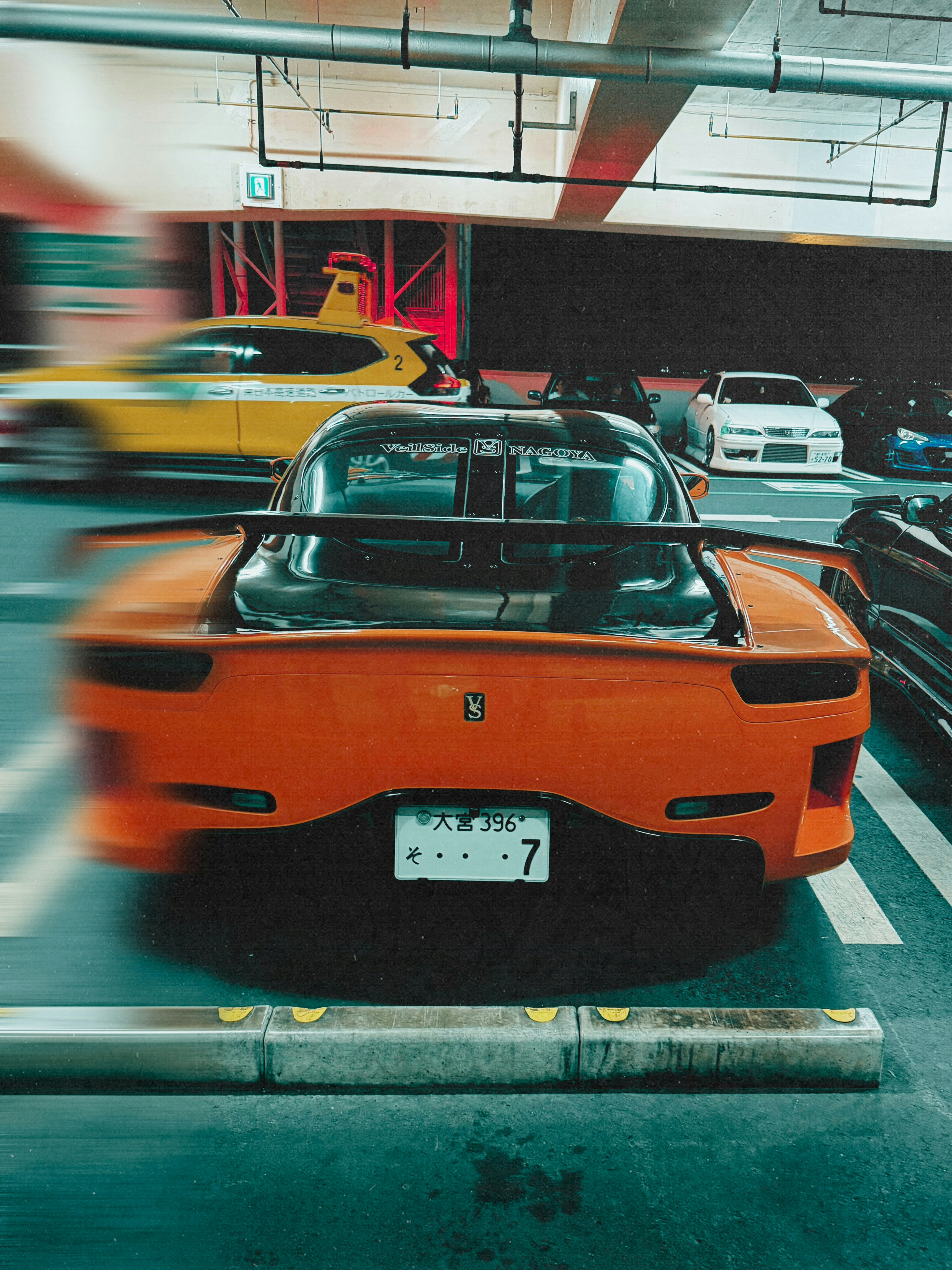 Orange sports car parked in a garage with motion blur.