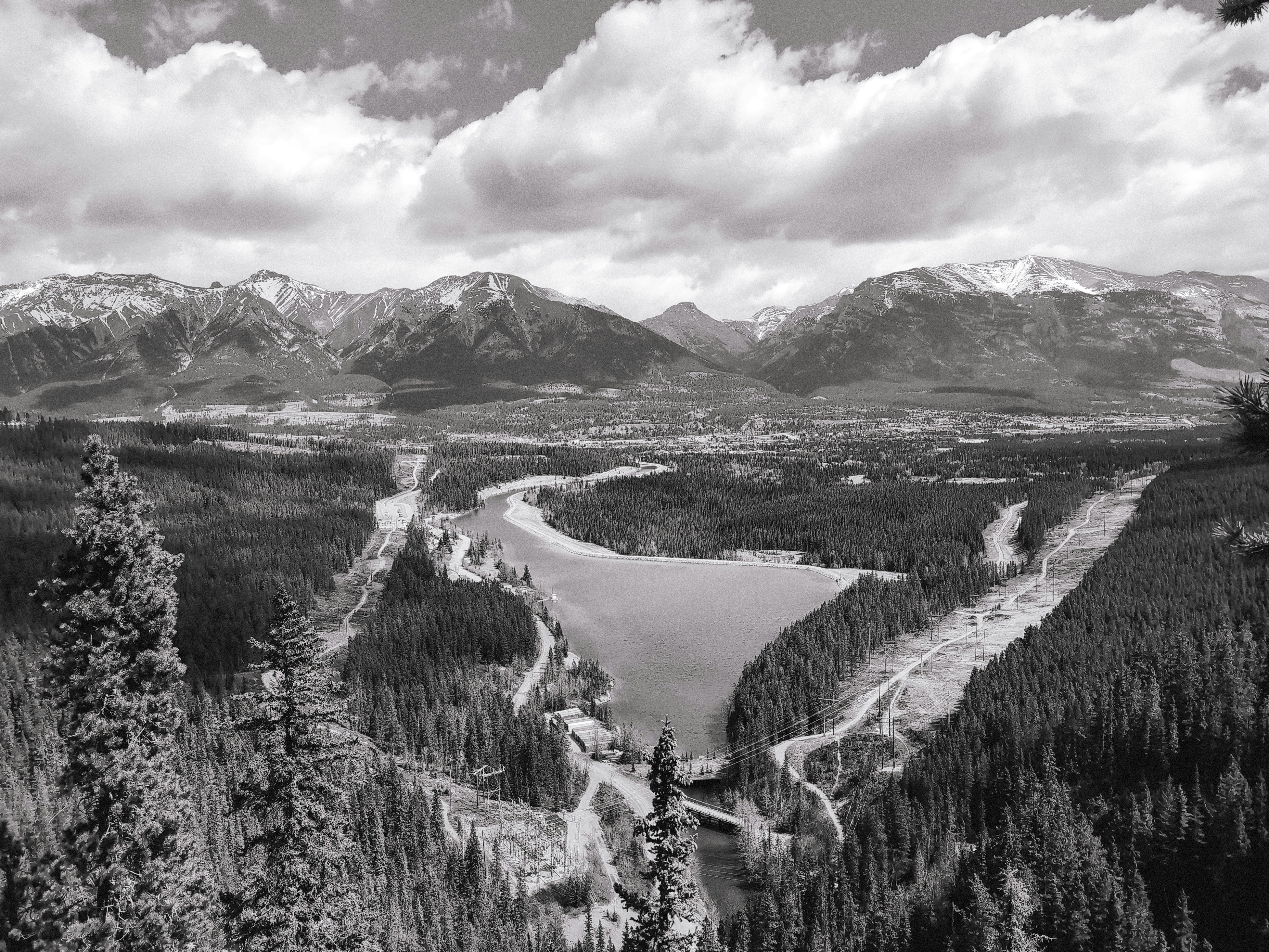 Snow-capped mountains overlook a forested valley and lake.