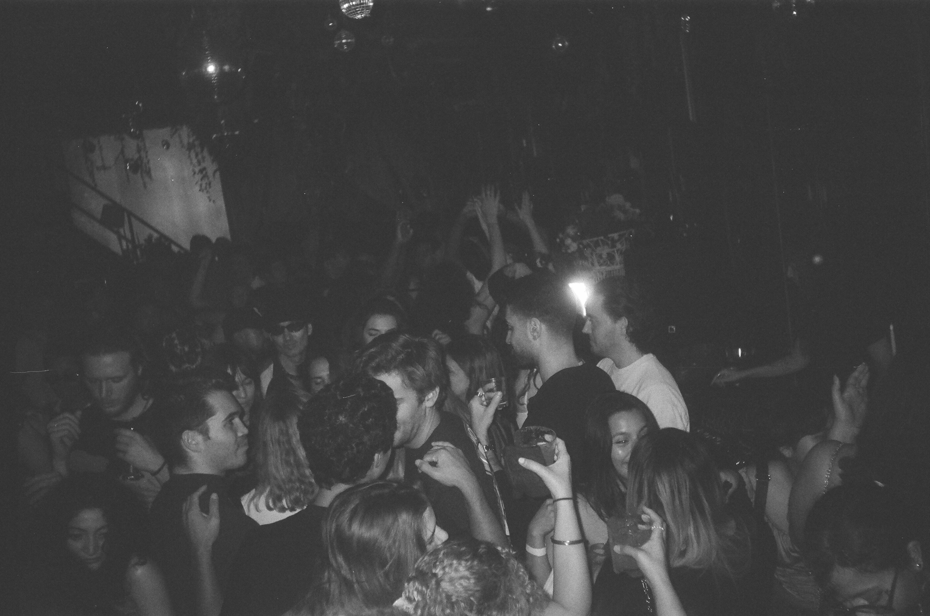 A crowded nightclub scene with people dancing in low light.