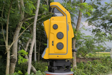 A yellow surveying instrument stands outdoors.