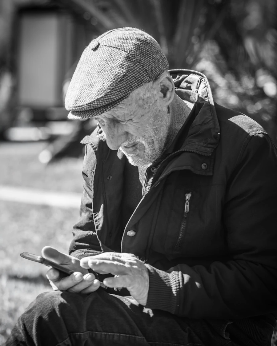 An older man in a cap reading his phone