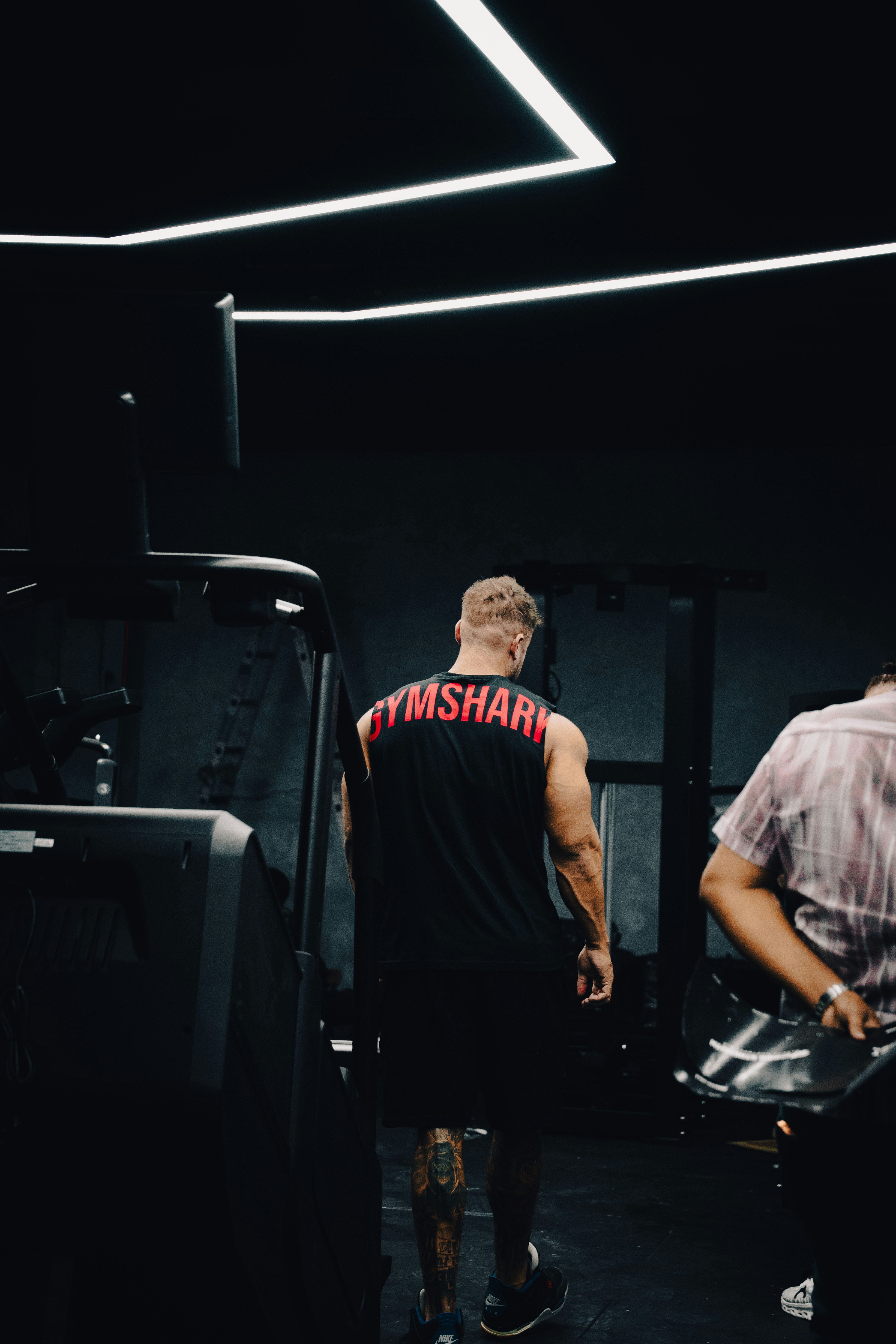 Uomo con la maglietta da squalo da palestra cammina in palestra buia.