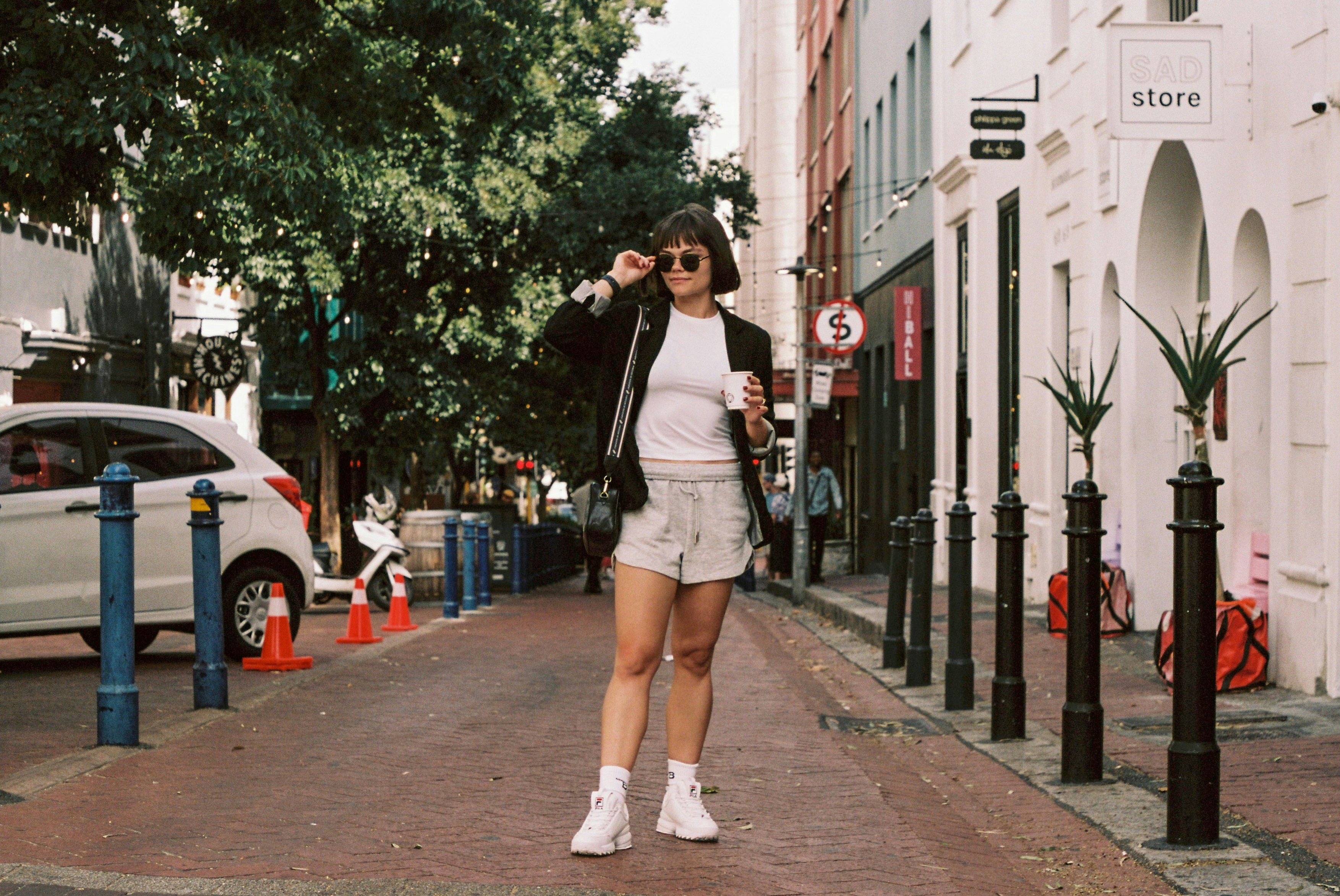 Woman walking down a cobblestone street with buildings.