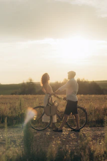 Couple with bicycle in field at sunset