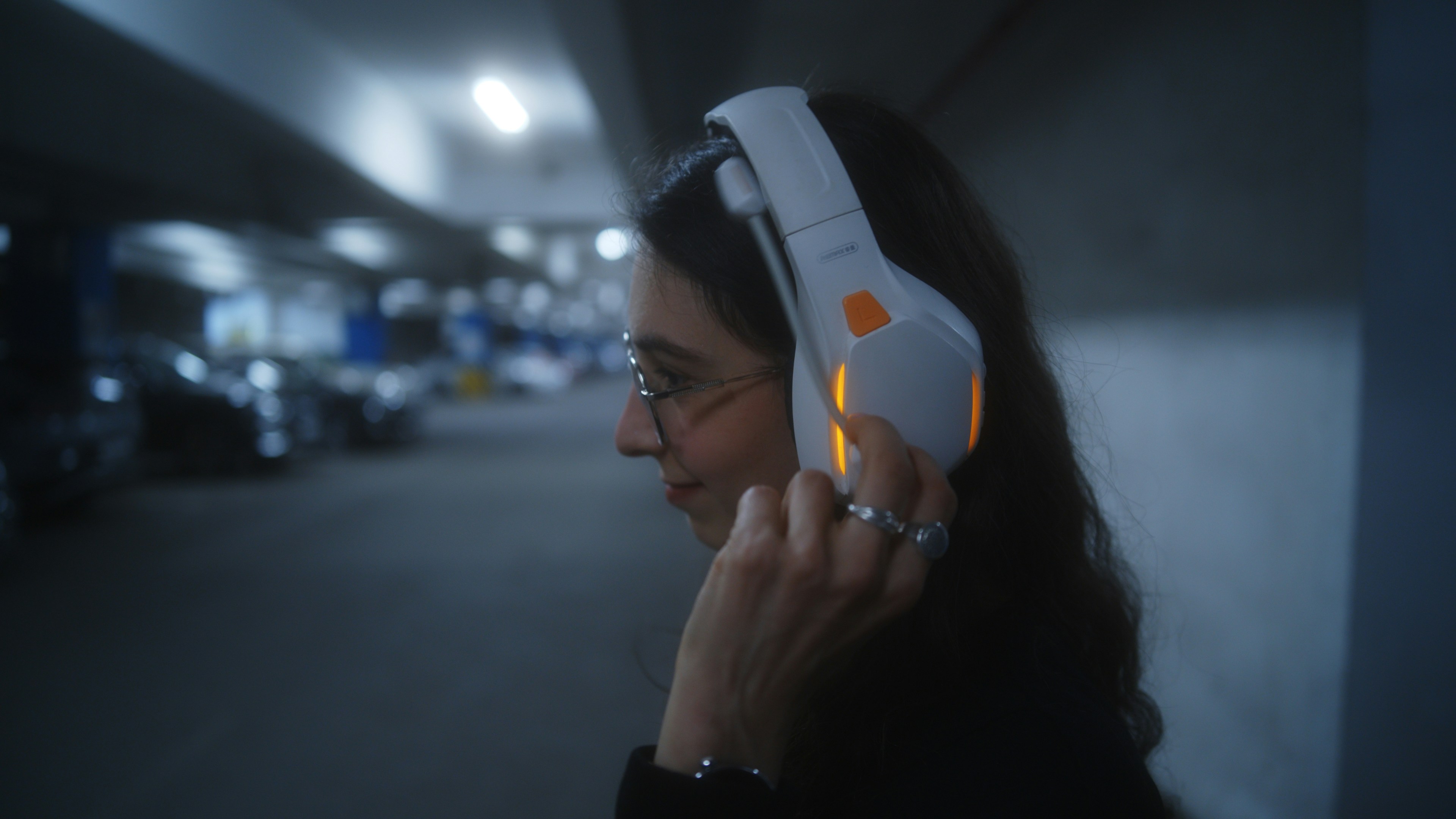 Woman wearing white headphones in a dark setting