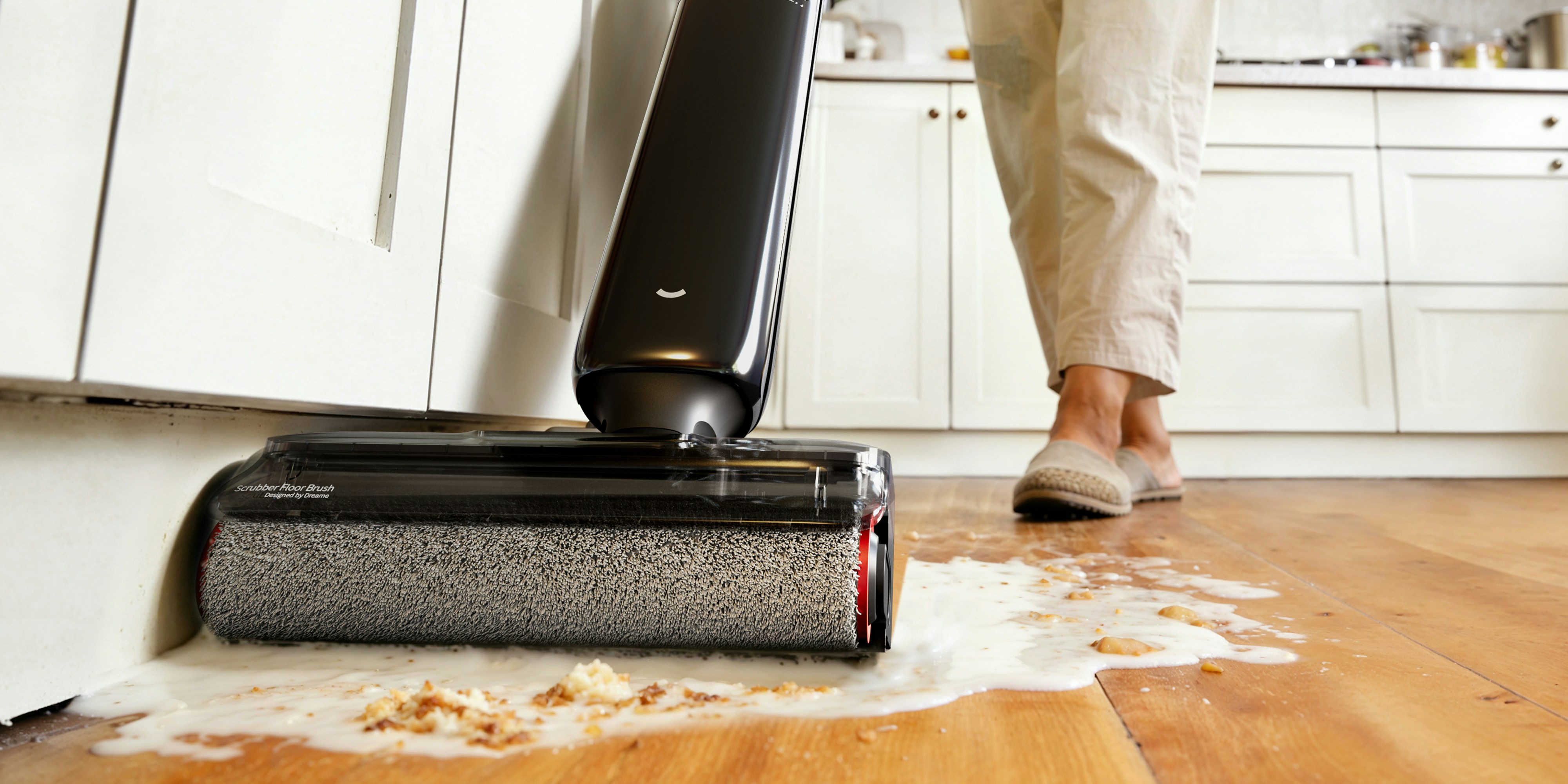 Person cleaning spilled liquid on wooden floor with vacuum