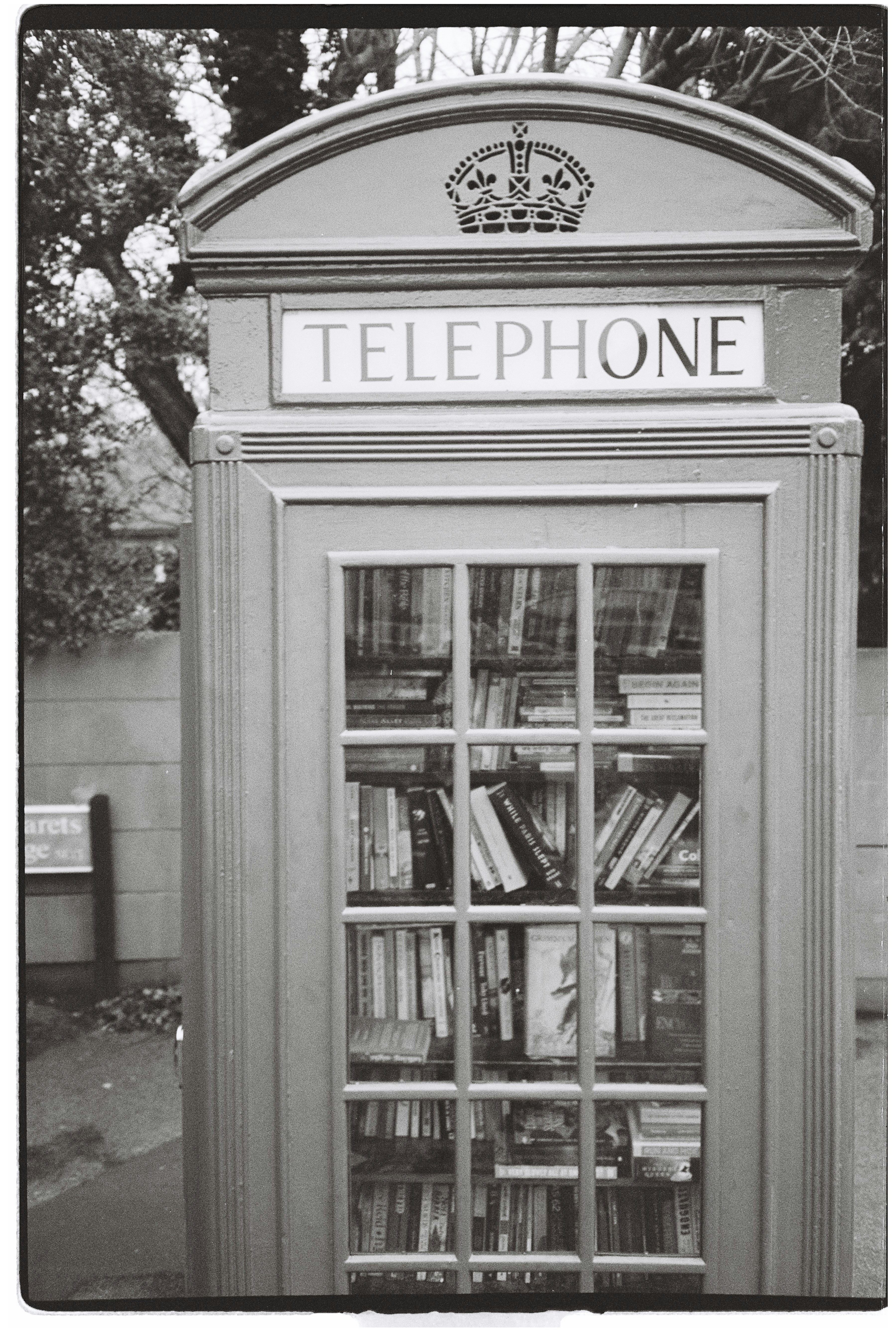 A vintage telephone booth filled with books.
