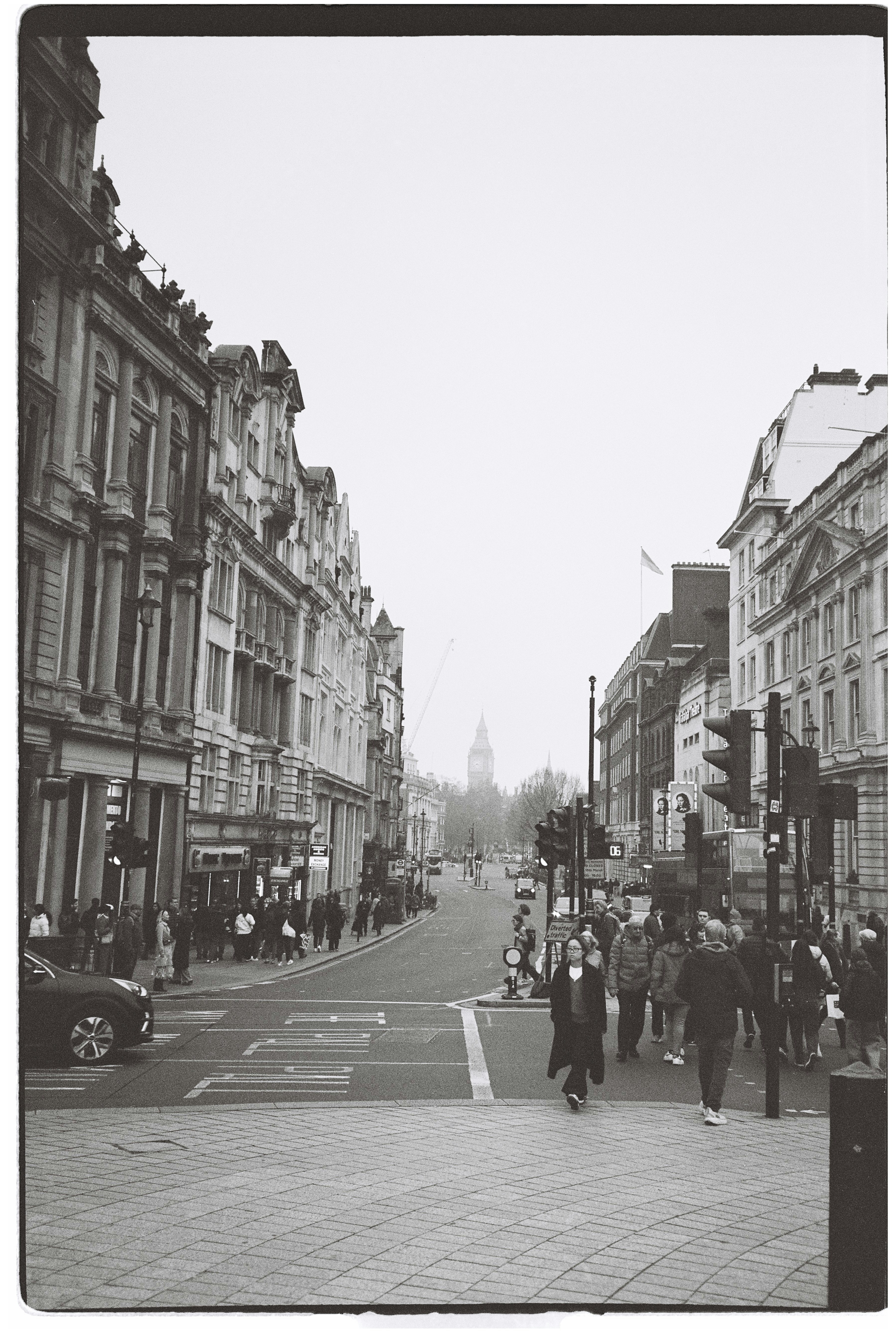 People walking on a street with buildings and clock tower.