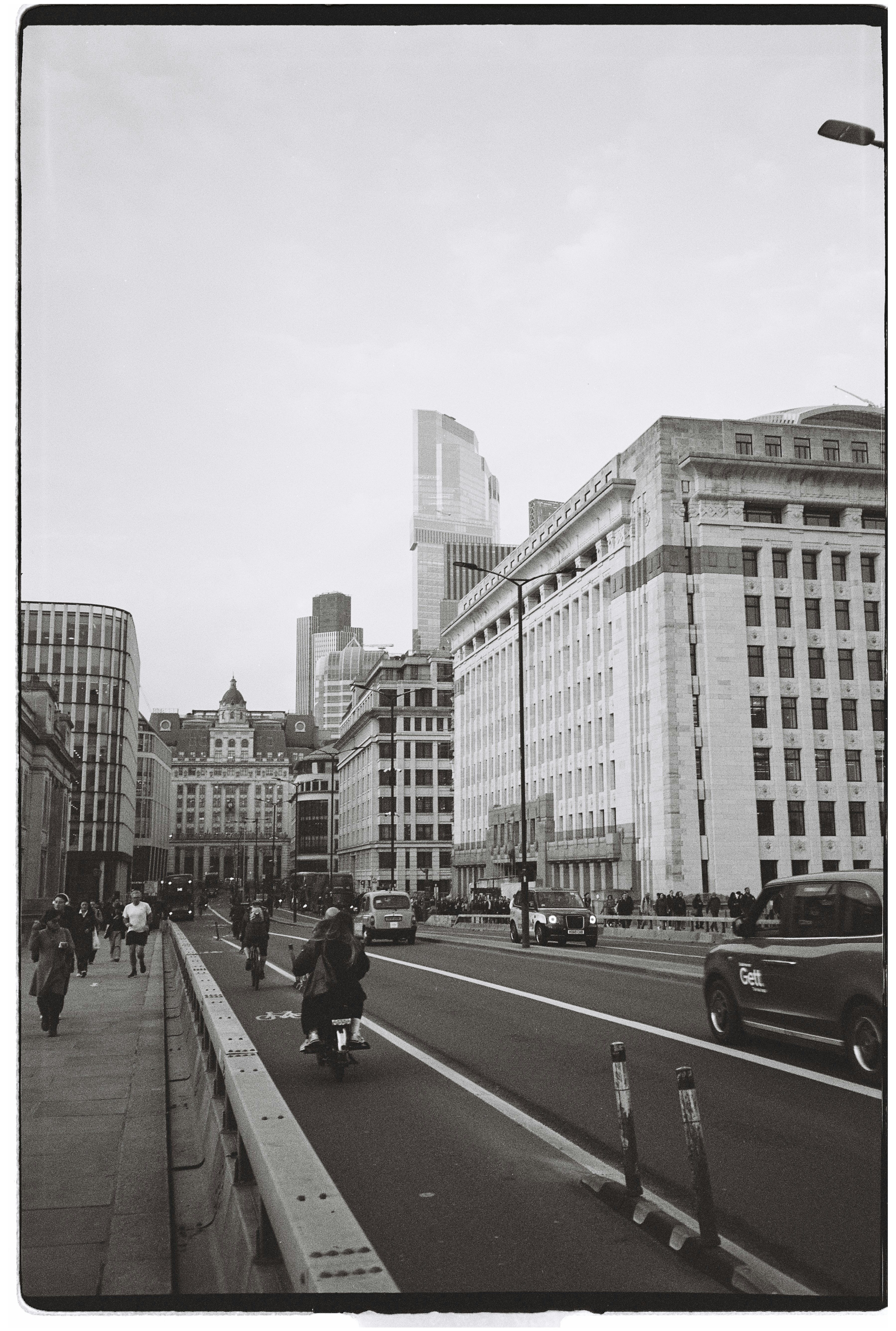 City street with cars, motorcycles, and pedestrians.