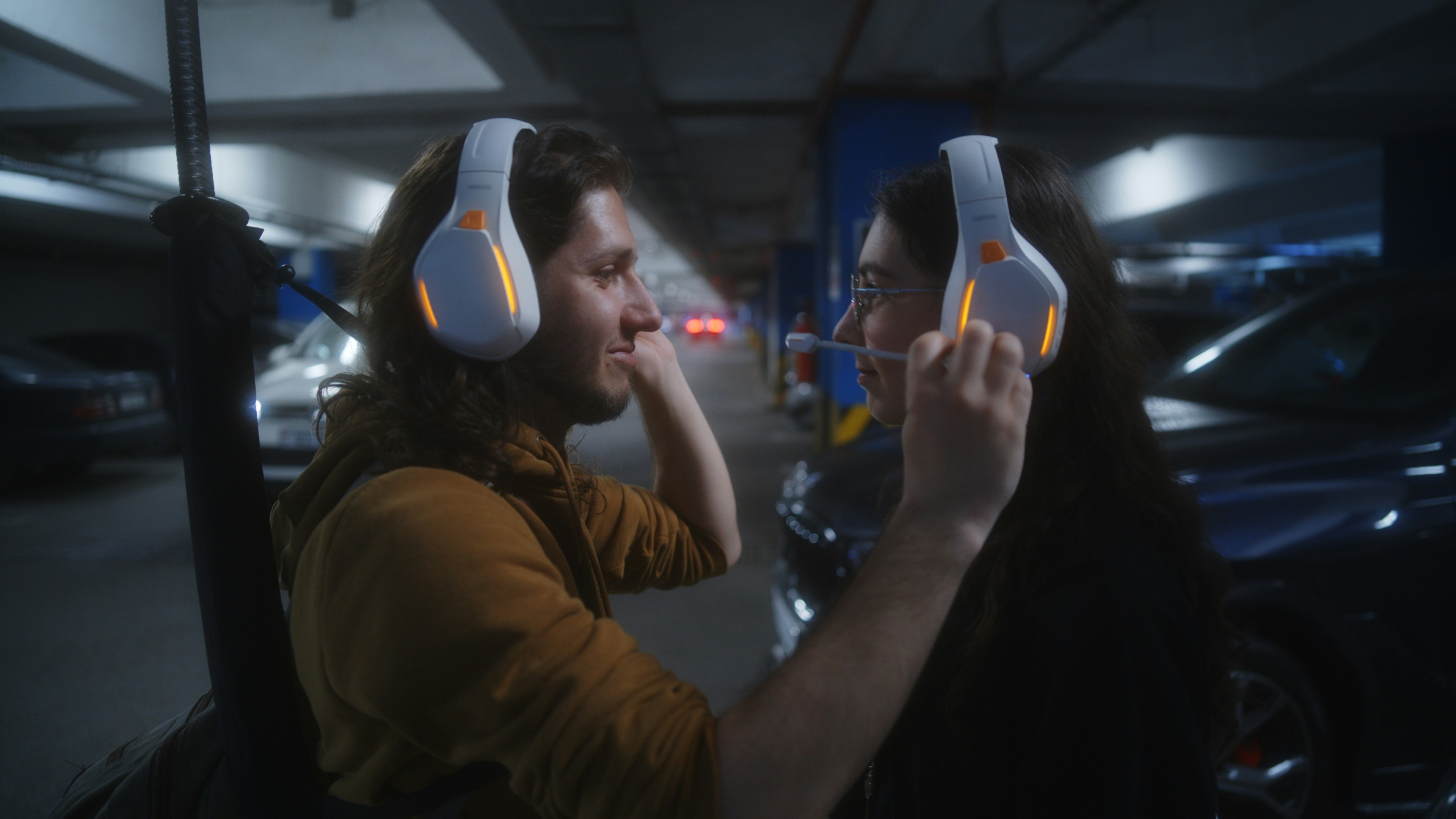 Couple wearing glowing headphones in a parking garage